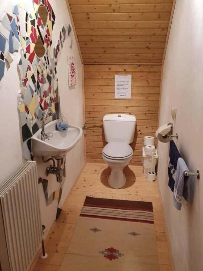 Kleines WC mit Holzvertäfelung, Waschbecken und farbiger Wandgestaltung.