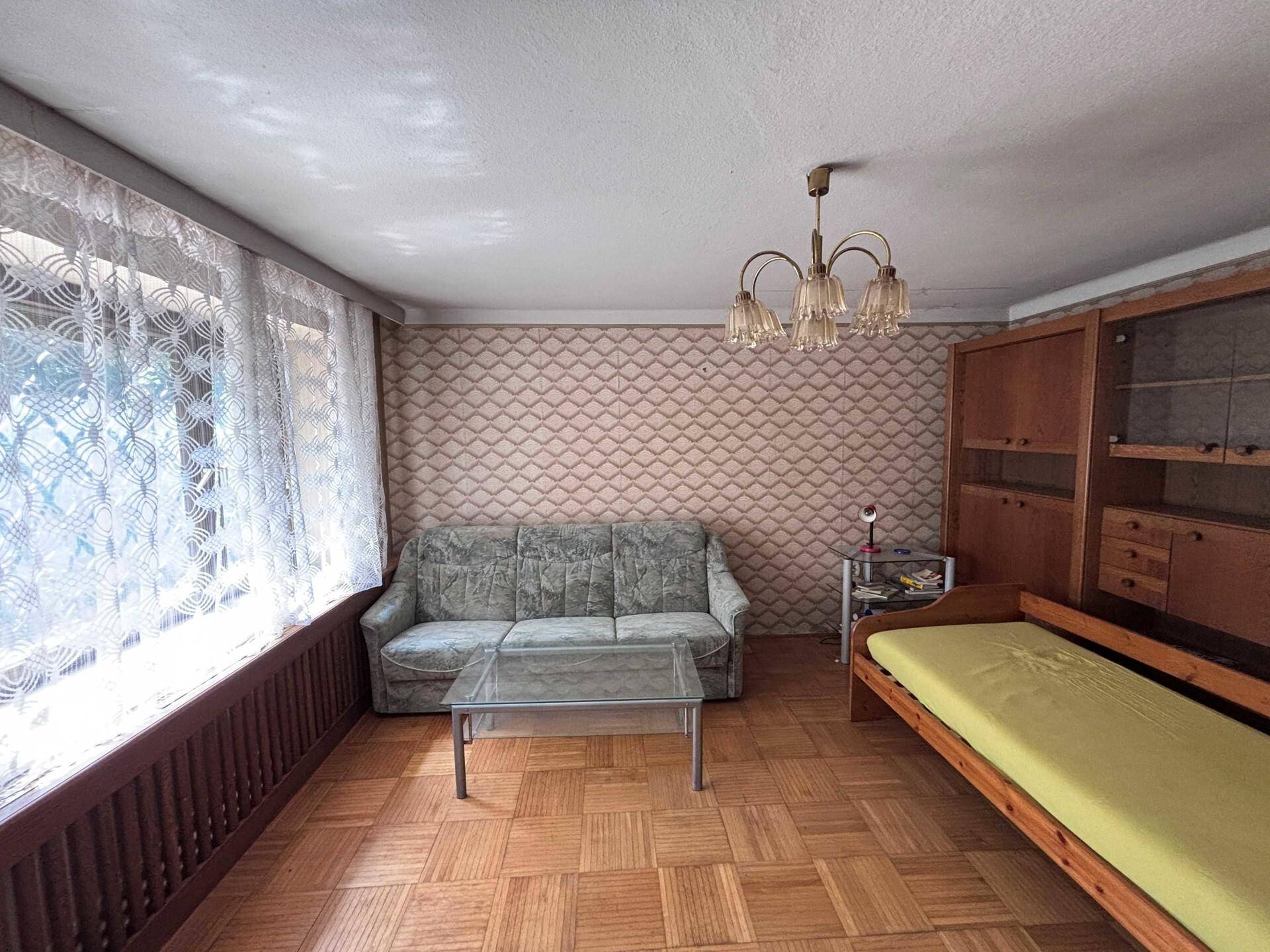 Gemütliches Wohnzimmer mit Sofa, Couchtisch, Schrankwand und Parkettboden.