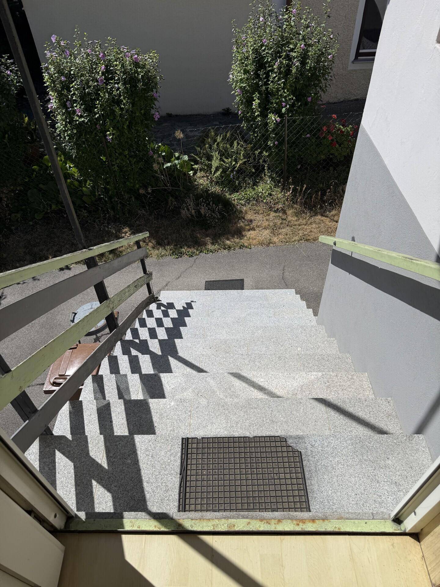 Steintreppe führt hinunter zu einem Eingang, mit Schattenmustern auf den Stufen.