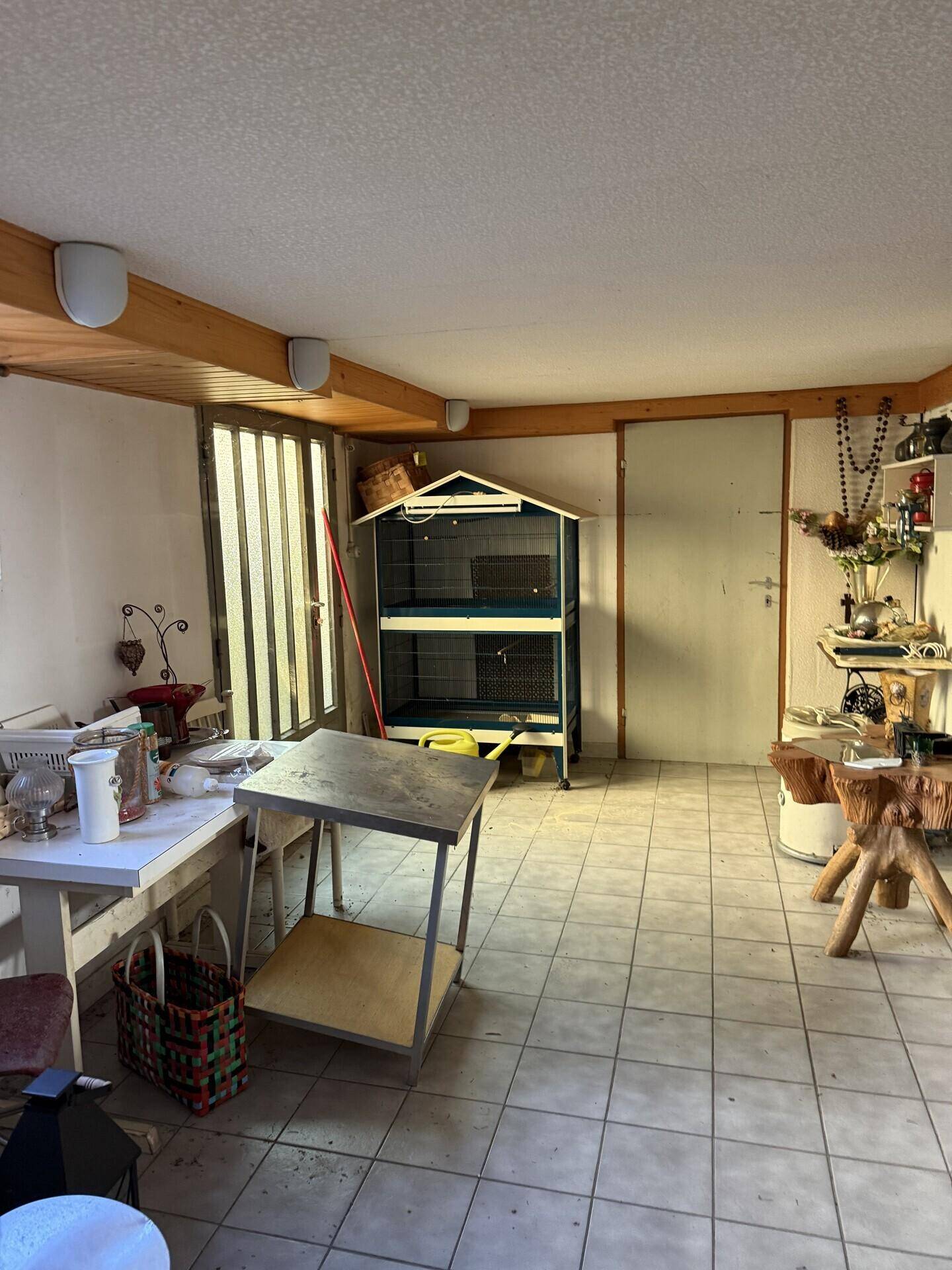 Mehrzweckraum mit Fliesenboden, Holzdecke und verschiedenen Gegenständen, vielseitig nutzbar.