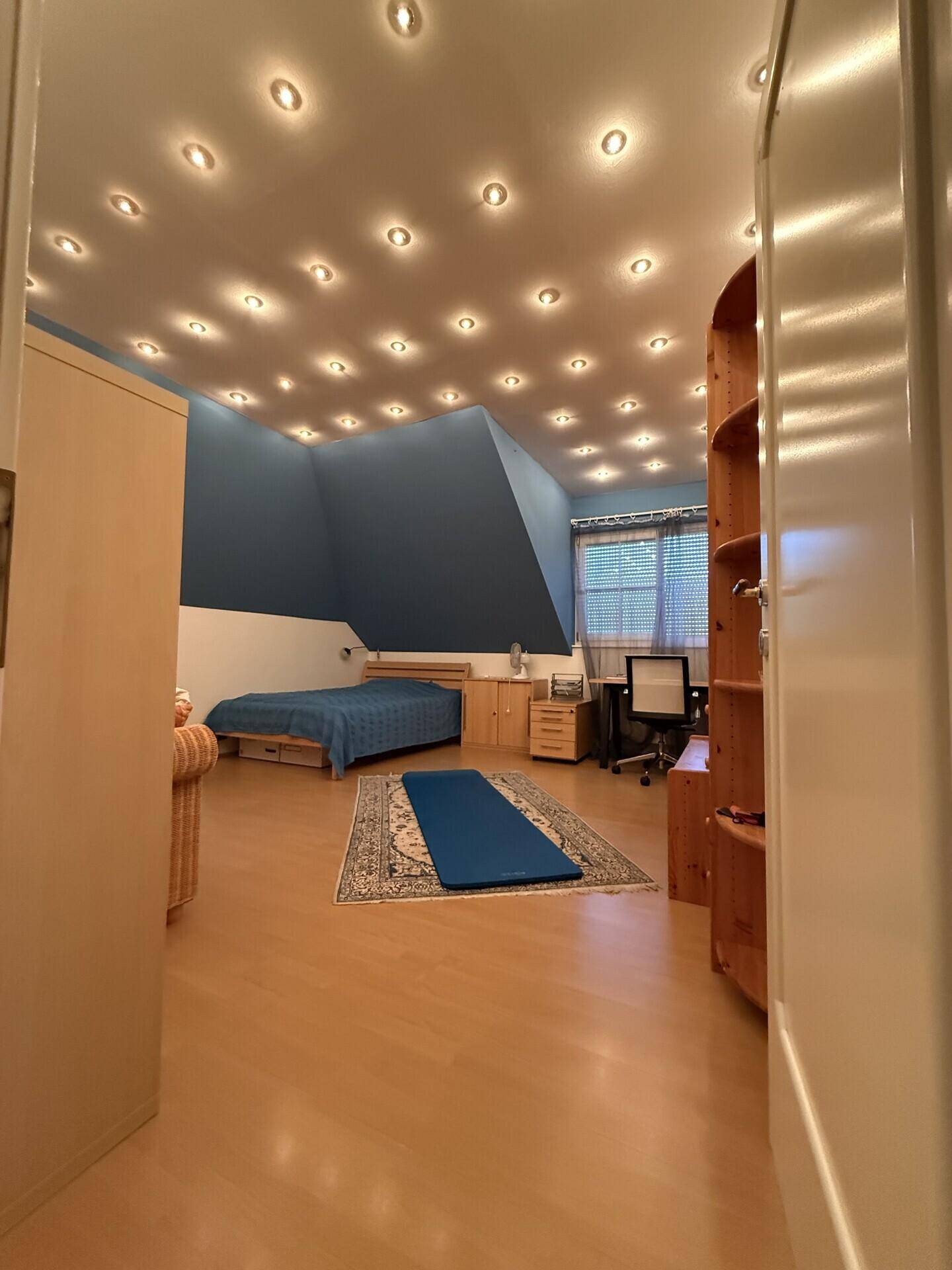 Geräumiges Schlafzimmer im Dachgeschoss mit Holzboden und Schreibtischbereich.