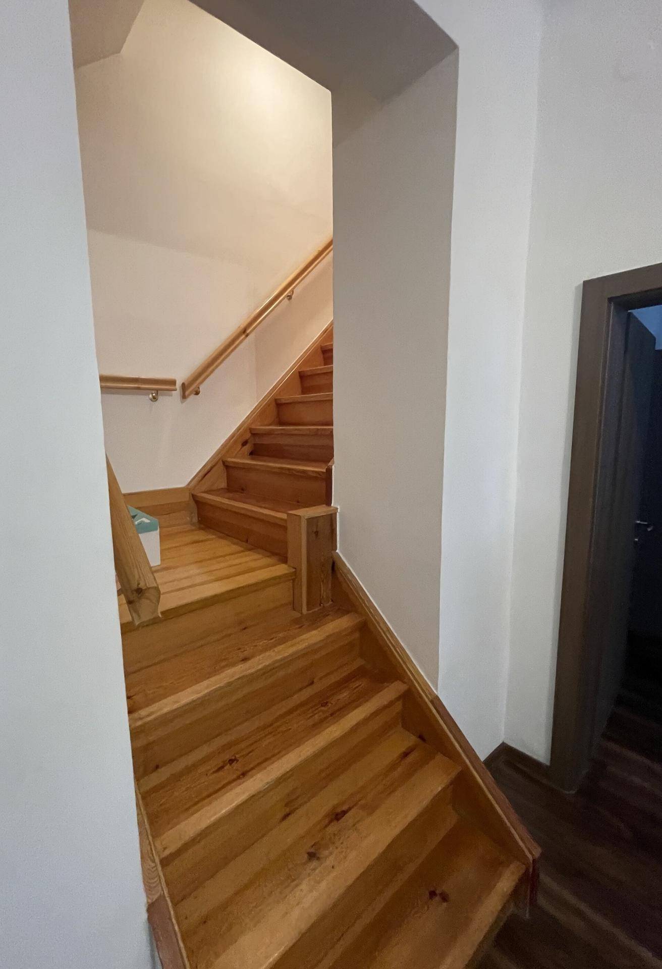 Holztreppe mit Geländer, die in die obere Etage führt.