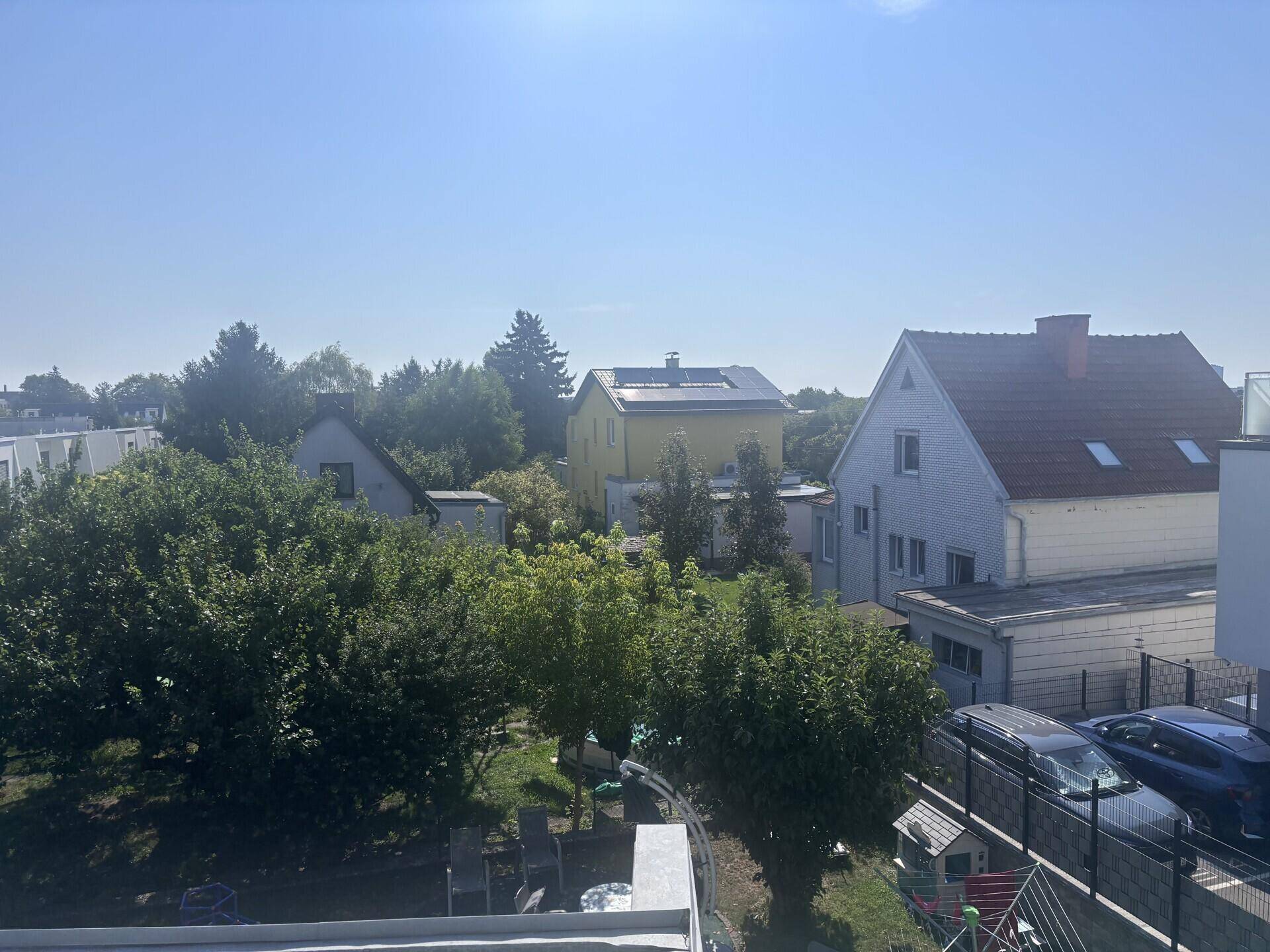 Weitläufiger Blick über eine Wohnsiedlung mit verschiedenen Häusern und viel Grün unter klarem Himmel.