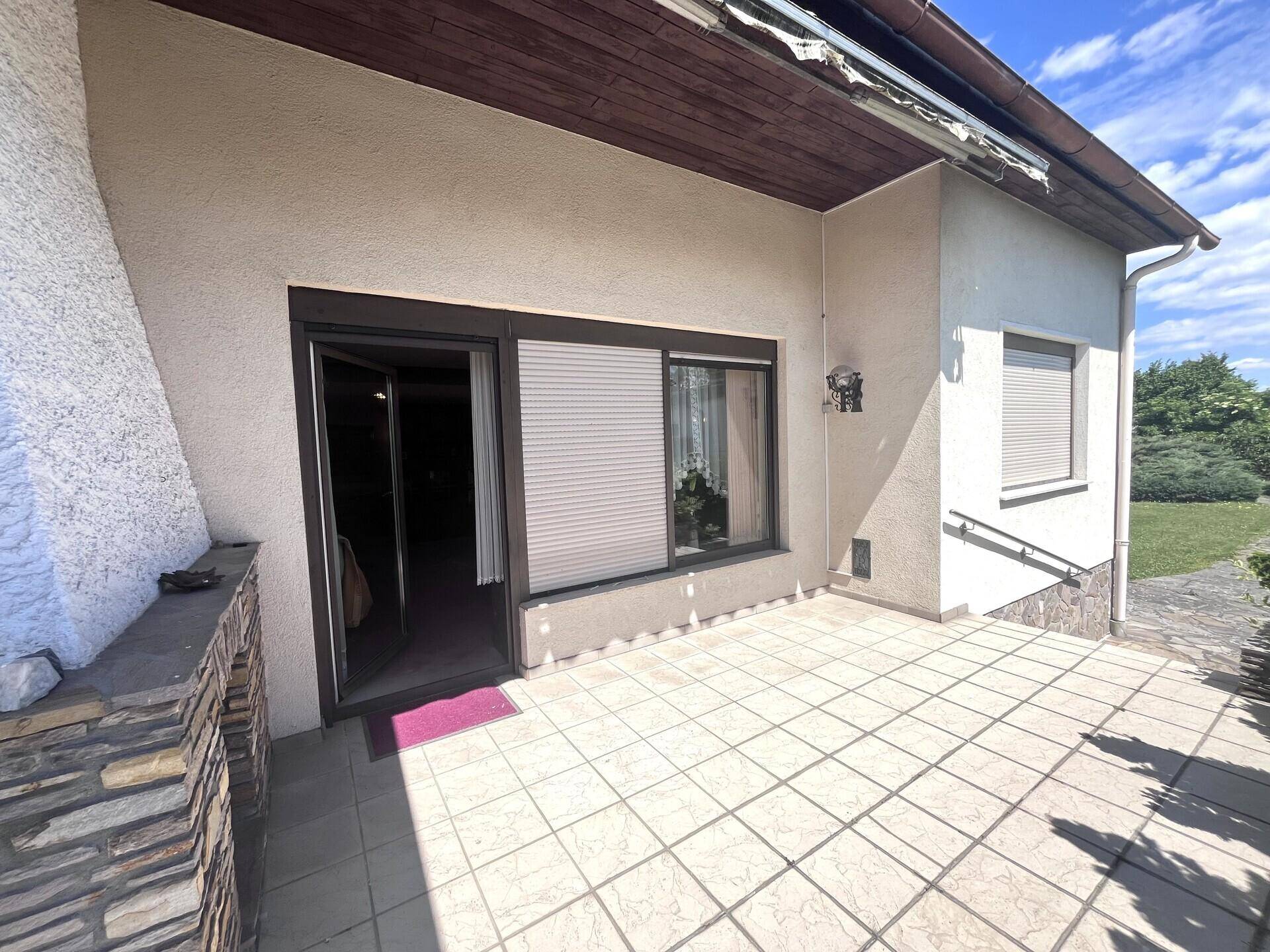 Geräumige Terrasse mit Fliesenboden und direktem Zugang zum Haus, ideal für entspannte Stunden im Freien.