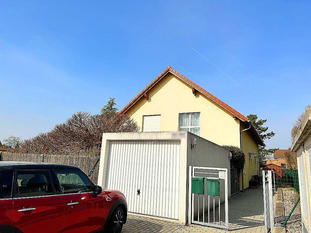 Rückansicht des Hauses mit integrierter Garage, gepflasterter Zufahrt und Briefkästen.