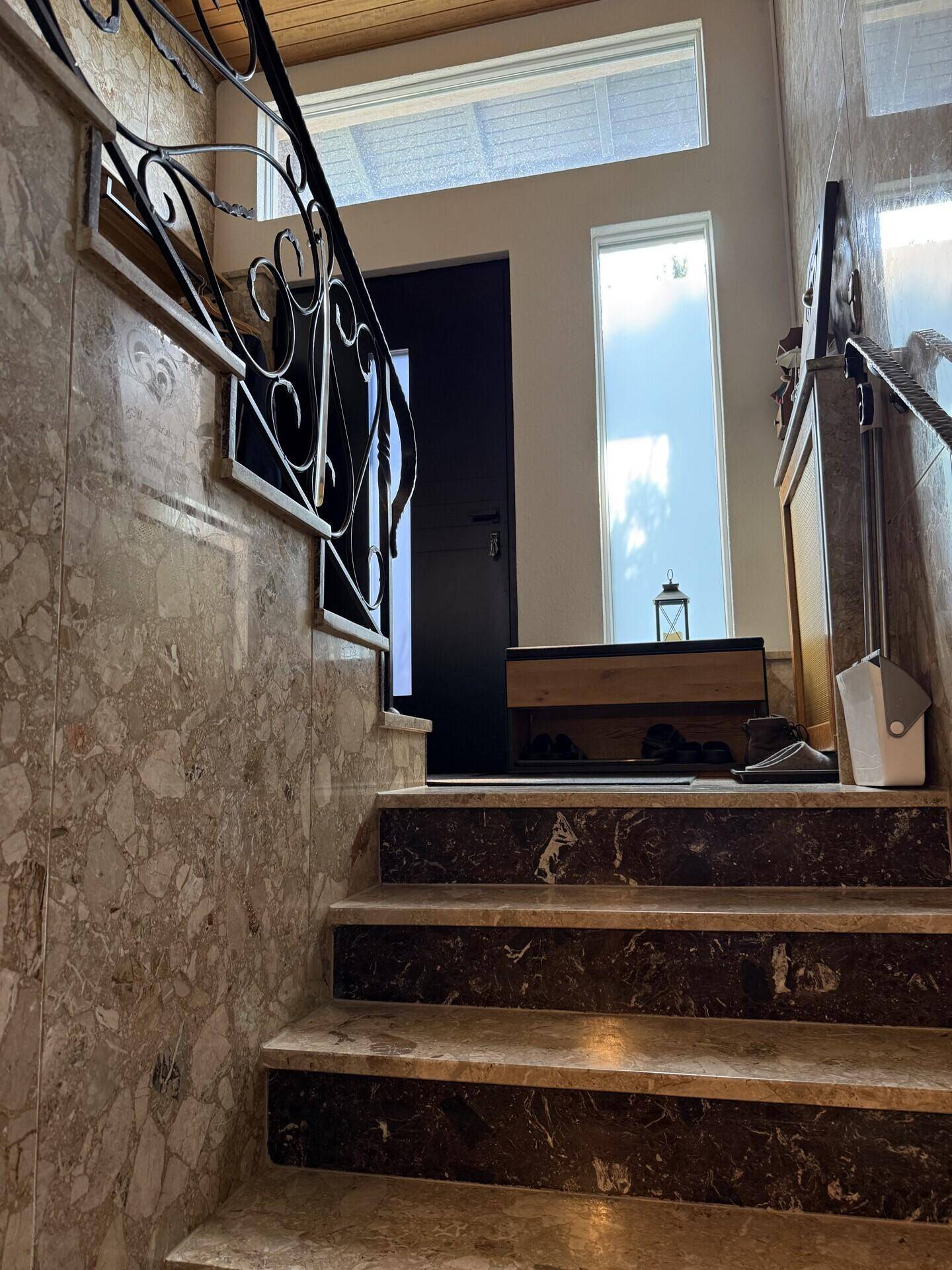 Elegante Marmortreppe mit schmiedeeisernem Geländer und hohen Fenstern für viel natürliches Licht.