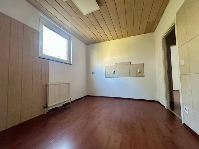 Raum mit Holzverkleidung an Wand und Decke, Laminatboden und einem Fenster für Tageslicht.