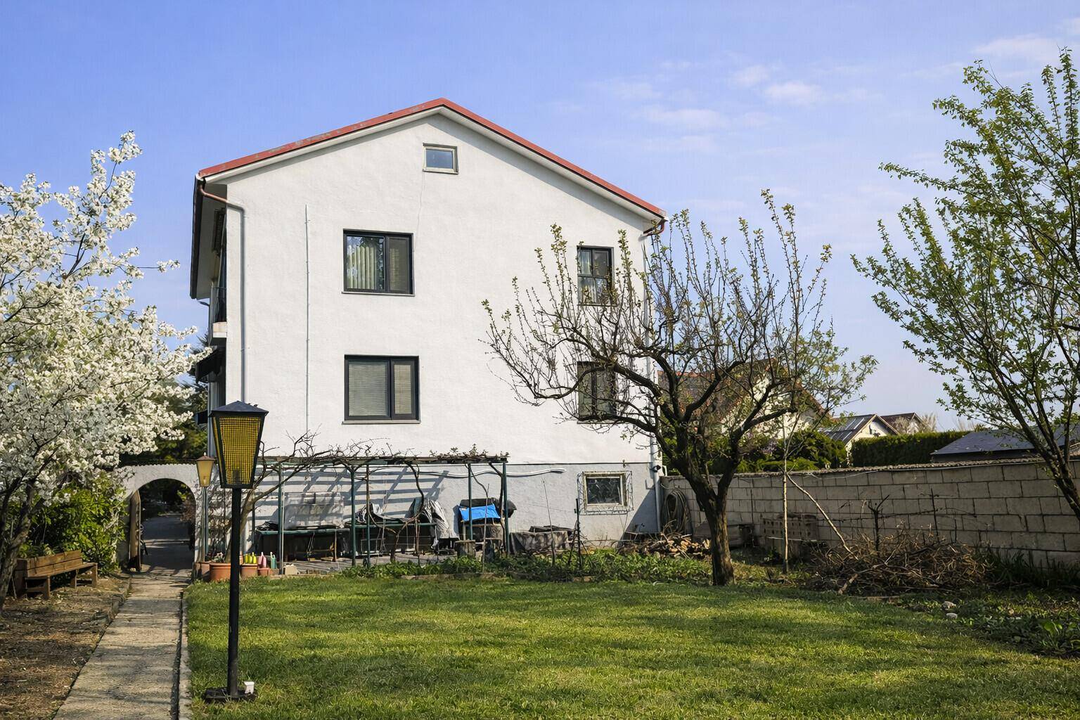 Rückseite des Einfamilienhauses mit Garten, Obstbäumen und einer kleinen Terrasse.