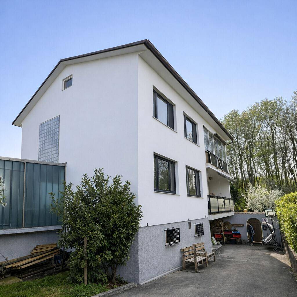 Modernisiertes Einfamilienhaus mit weißer Fassade, Balkon und gepflegtem Außenbereich.