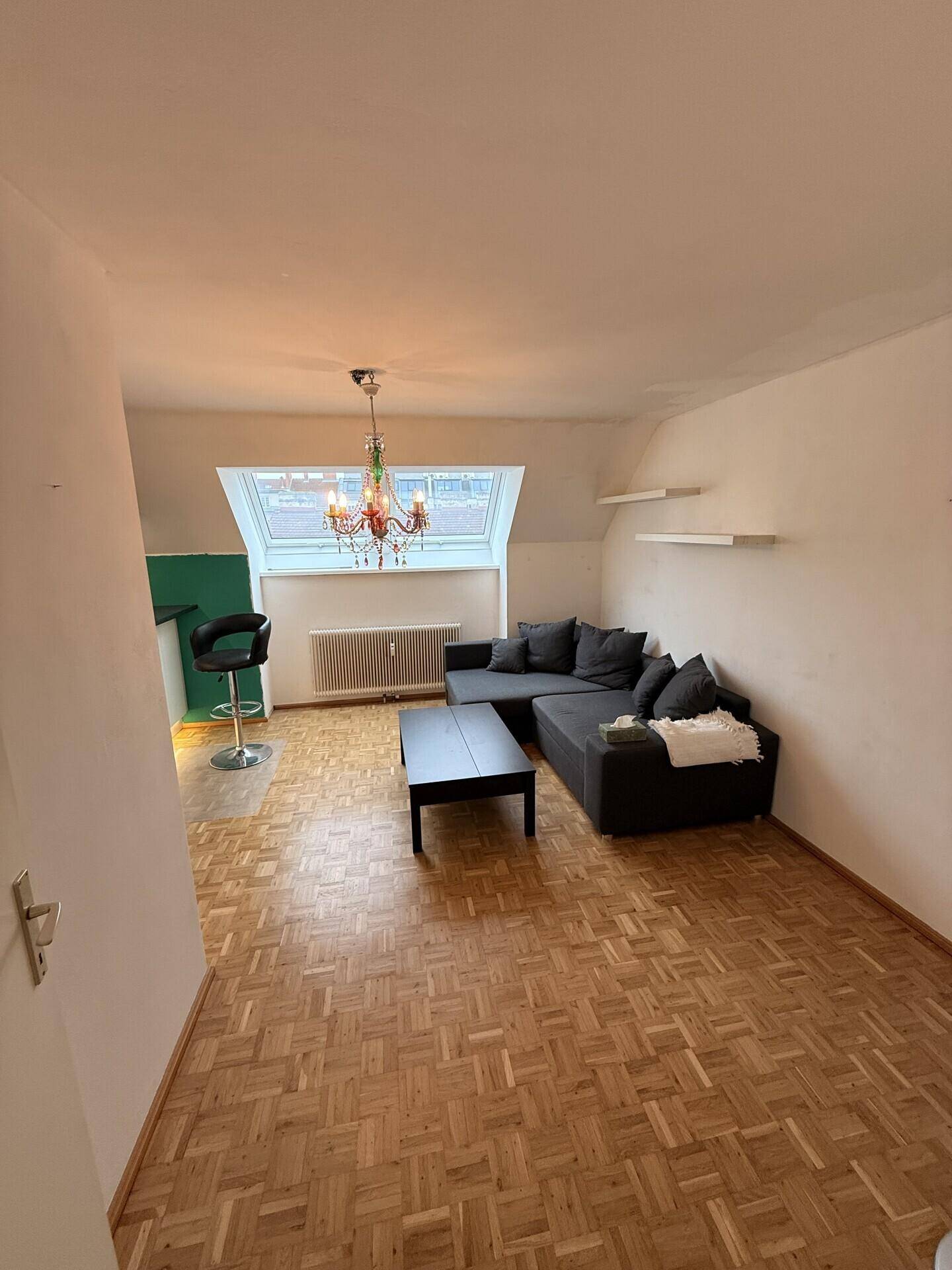Wohnbereich mit Parkettboden, gemütlichem Sofa und Dachfenster, offen gestaltet.