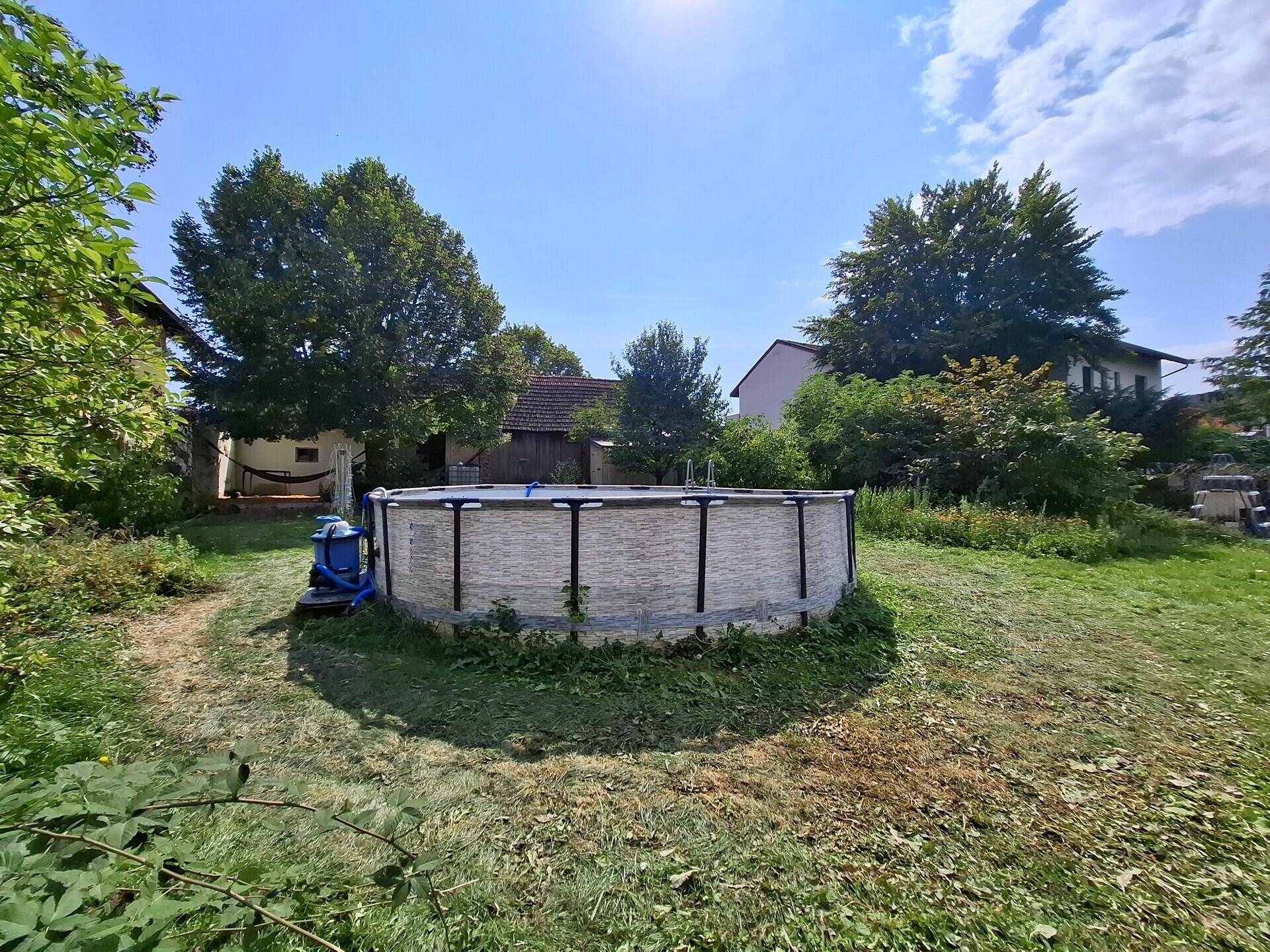 Sonnige Gartenansicht mit einem aufgestellten Pool und viel Platz für Freizeitaktivitäten.
