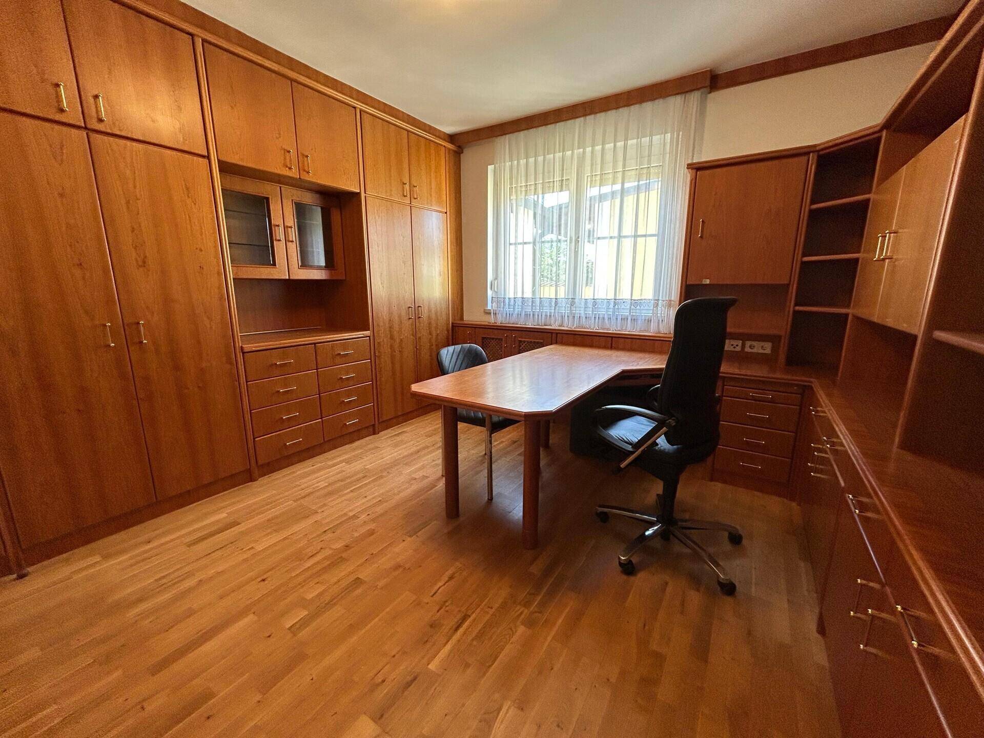 Arbeitszimmer mit umfangreichen Holz-Einbaumöbeln, Schreibtisch und Parkettboden.