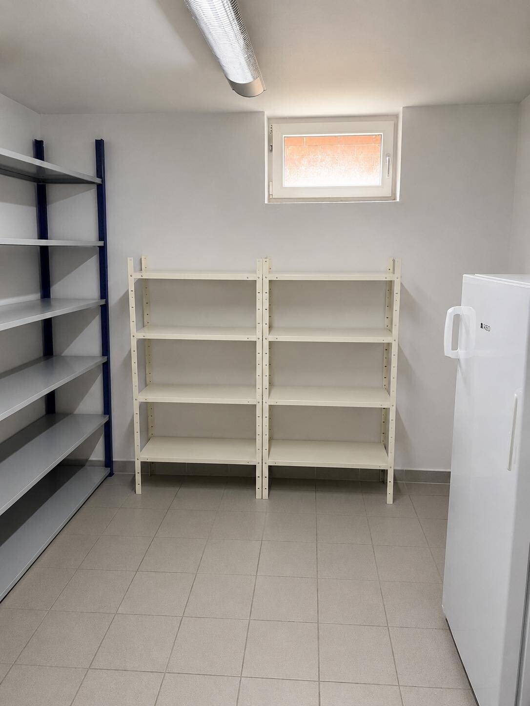 Geräumiger Abstellraum im Keller mit praktischen Regalen und einem zusätzlichen Kühlschrank.