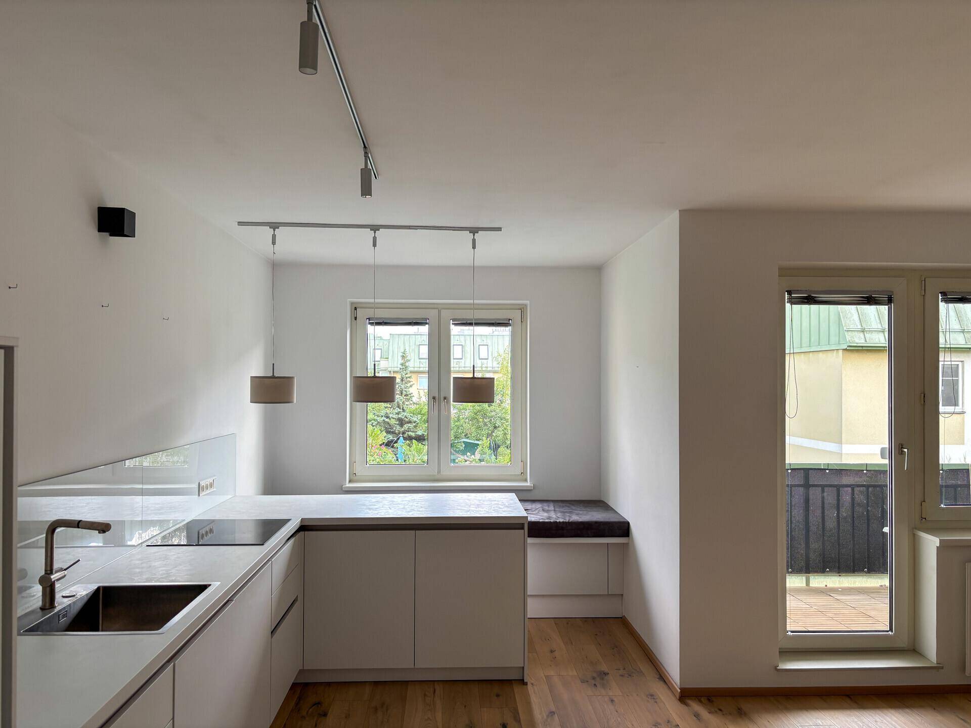 Helle Küche mit Fensterblick ins Grüne und Zugang zu einem Balkon.