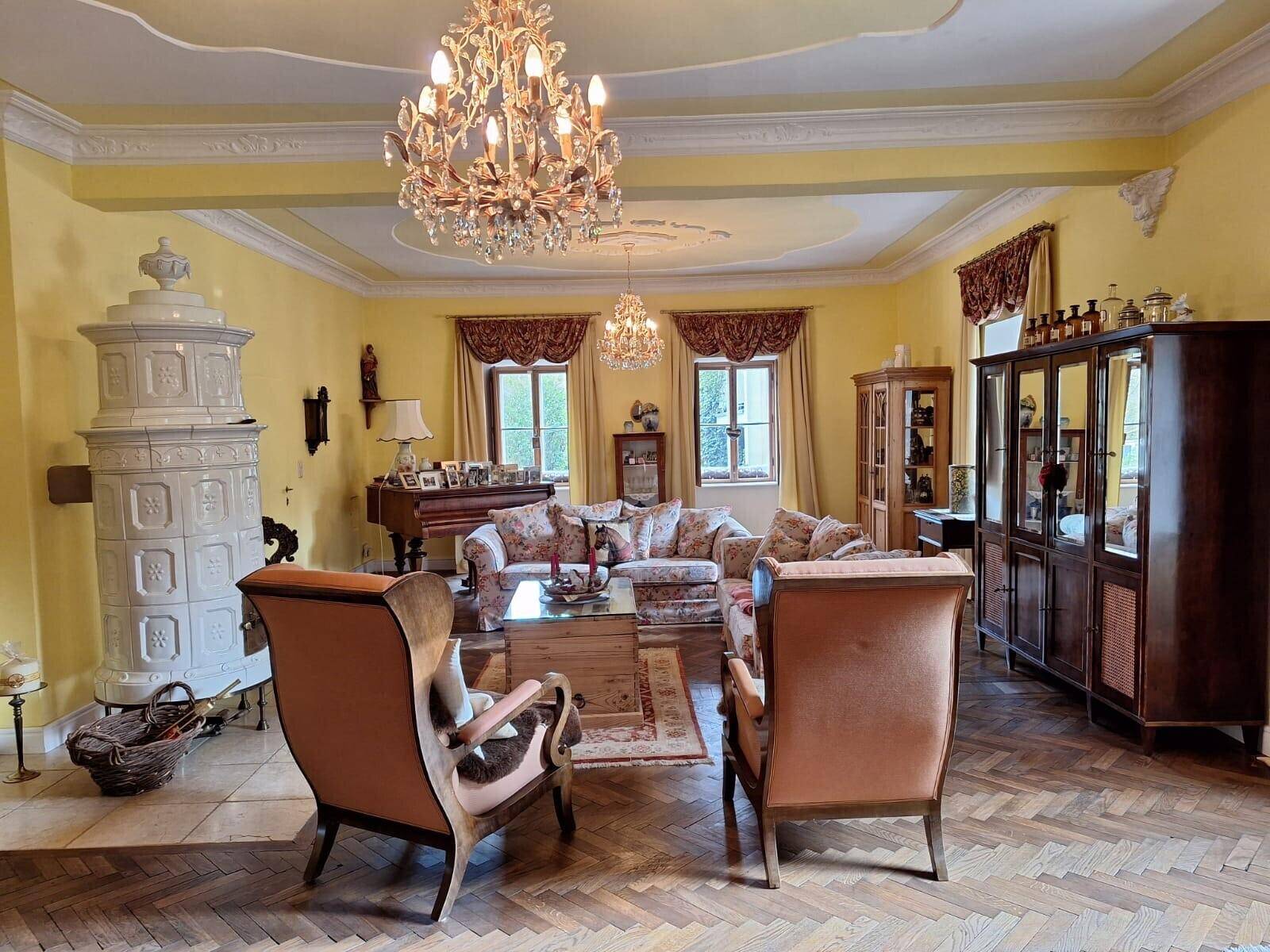 Elegantes Wohnzimmer mit Stuckdecke, Kachelofen und traditionellen Möbeln.