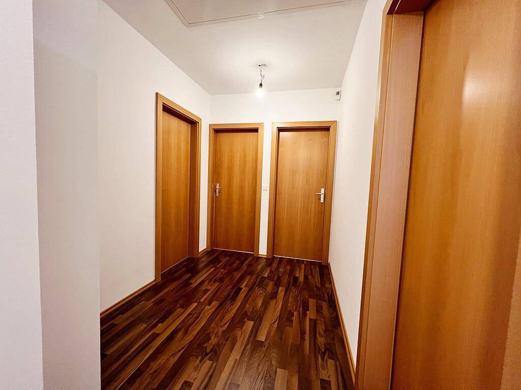 Oberer Flur mit Laminatboden und mehreren Holztüren, die zu den angrenzenden Räumen führen.