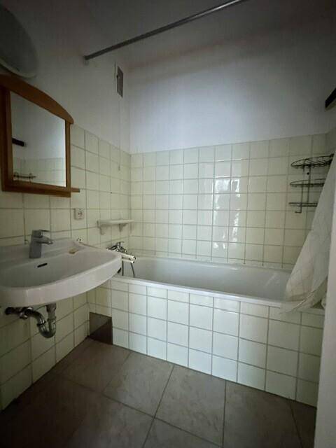 Gefliestes Badezimmer mit Badewanne, Waschbecken und Spiegelschrank in hellem Design.