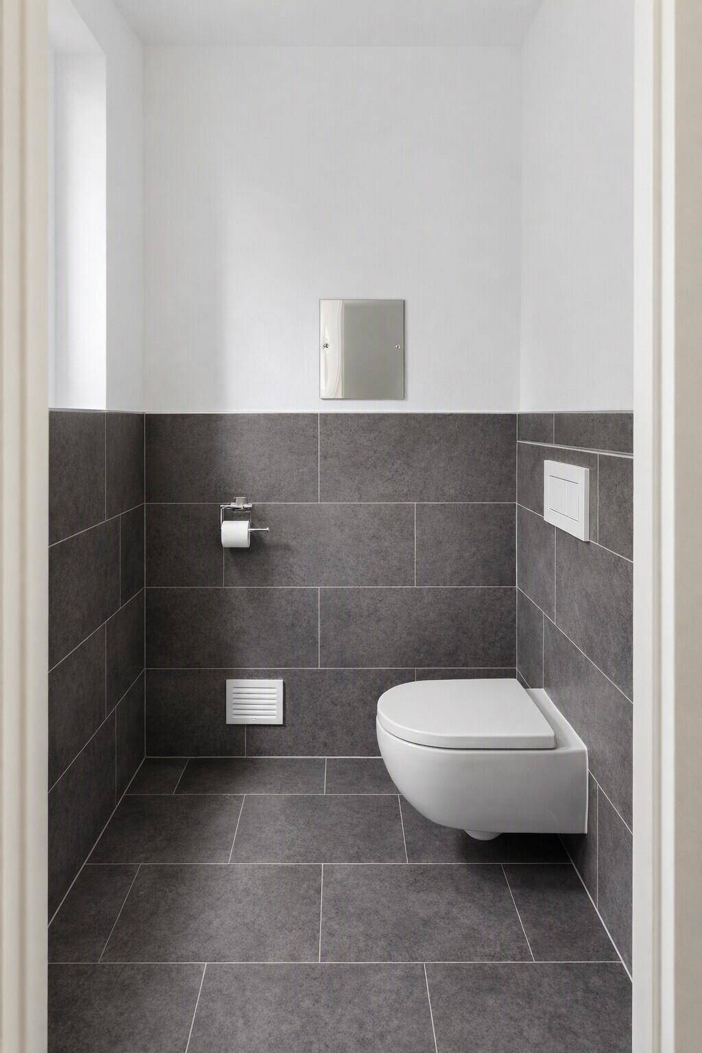 Separates WC mit Wand-WC und modernen grauen Fliesen, minimalistisch gestaltet.