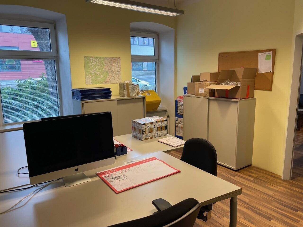 Büro mit gelben Wänden, Holzboden und einem Schreibtisch mit Computer, umgeben von Ablageschränken.