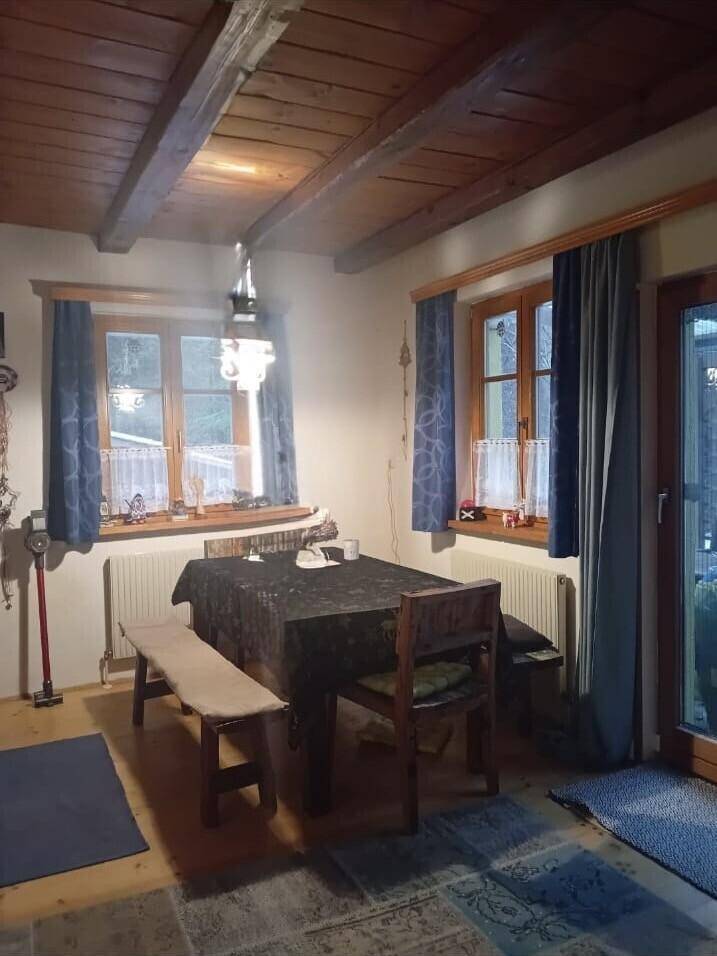 Rustikaler Essbereich mit Holzbalkendecke, Holztisch und Blick in den Garten.