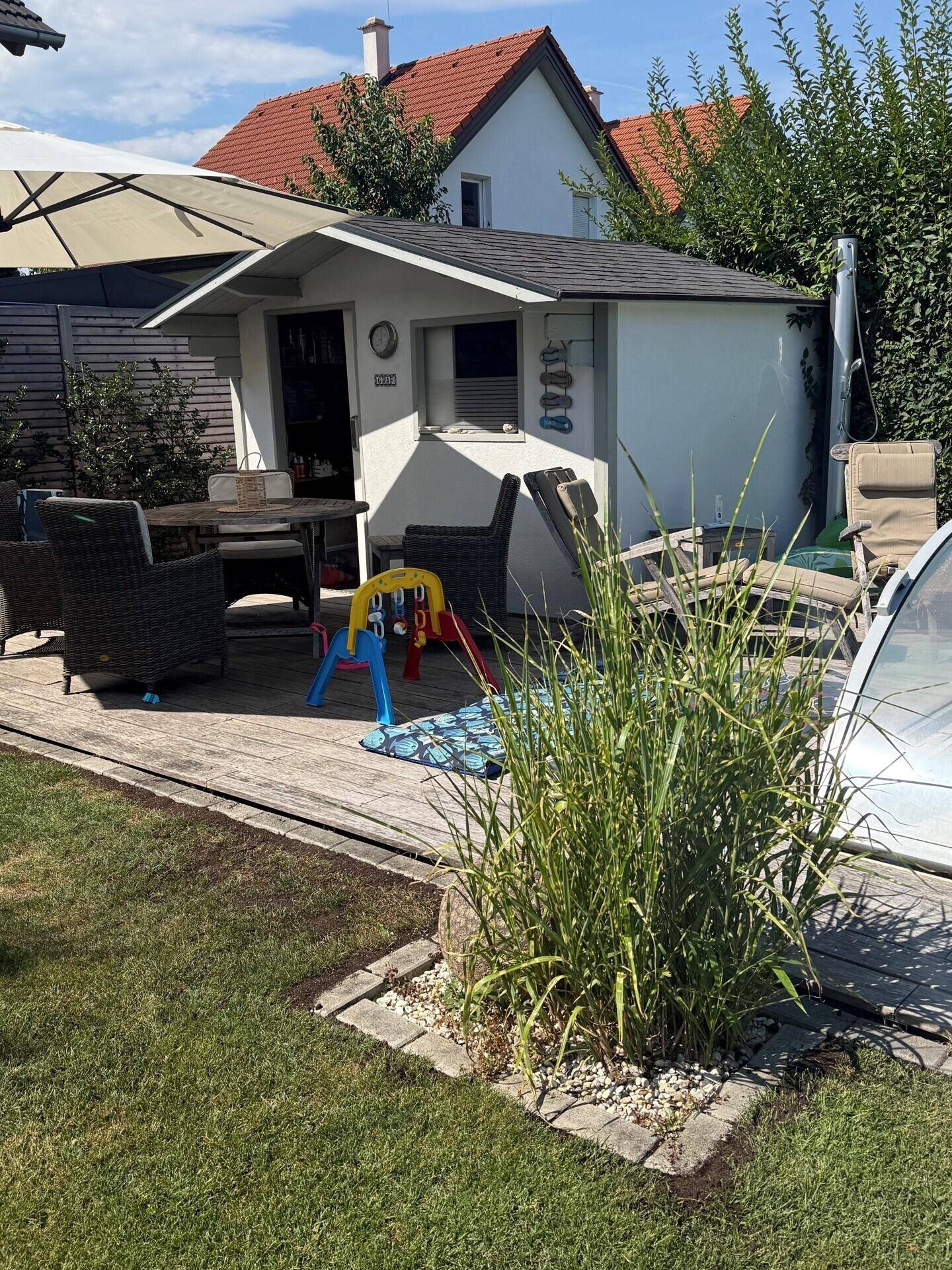 Gemütlicher Gartenbereich mit Gartenhaus, Essbereich im Freien und üppiger Bepflanzung.