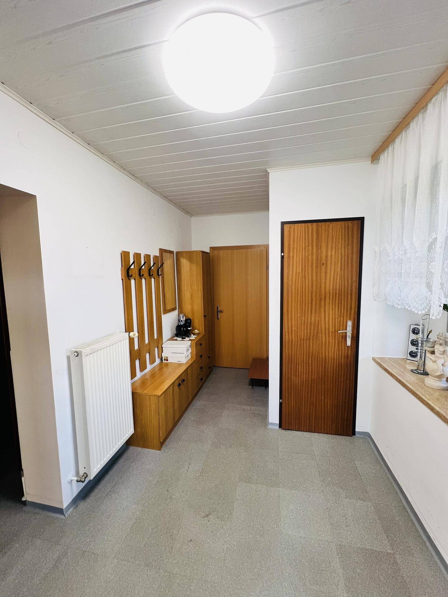 Heller Flur mit Garderobe, Holztüren und einem Fenster.