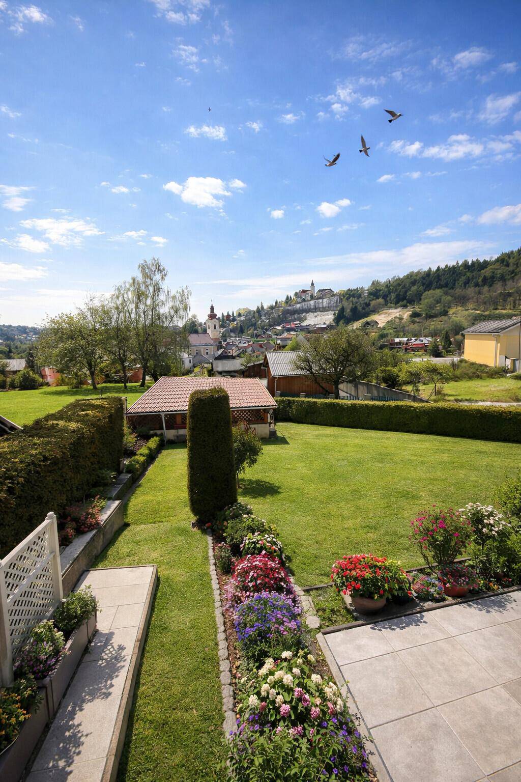Blick von der oberen Terrasse über den gepflegten Garten auf die umliegende Ortschaft.