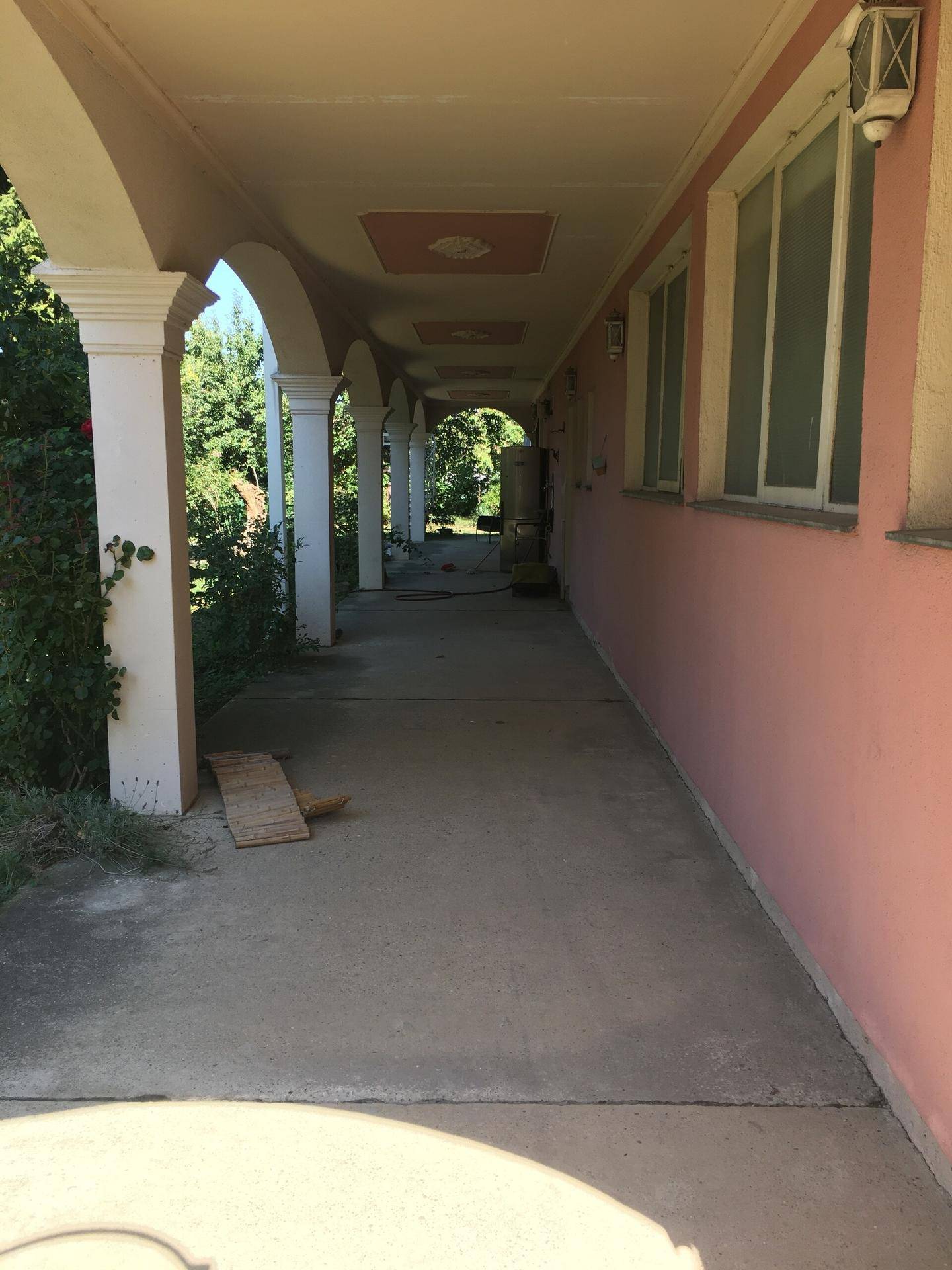 Lange, überdachte Veranda mit Säulen und Bögen entlang der Hausseite.