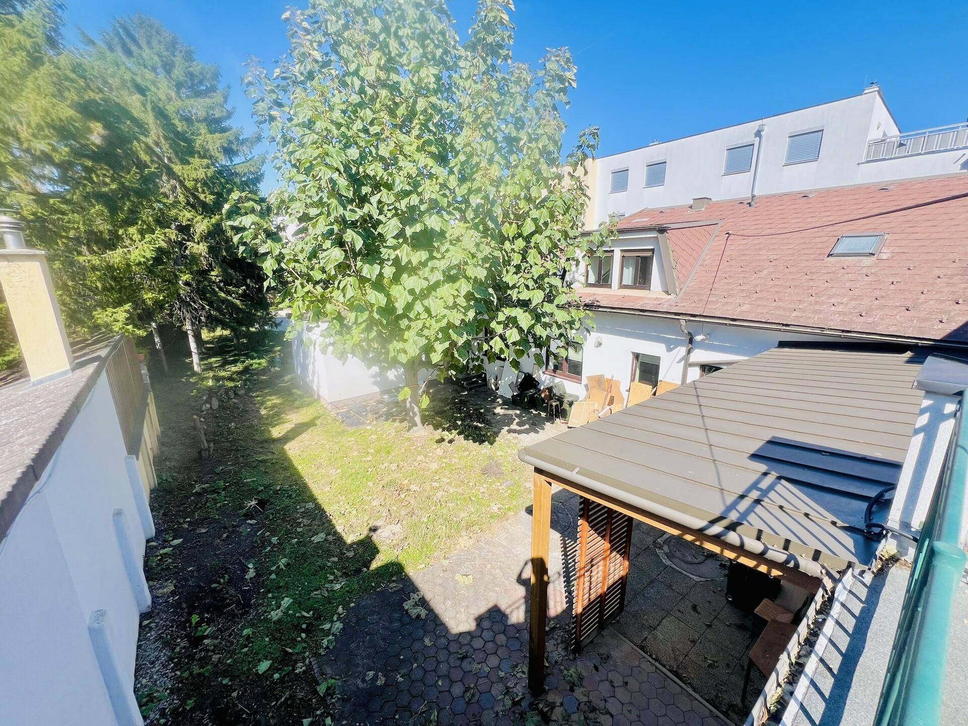Vogelperspektive auf den Gartenbereich mit Terrasse und Baumbestand.