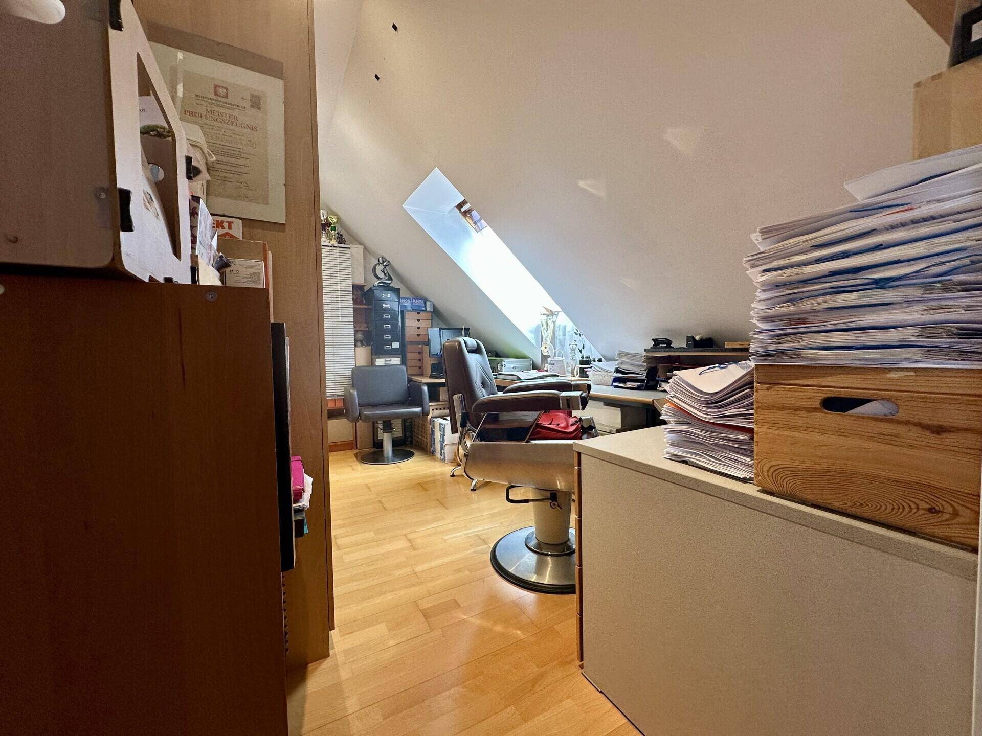 Büro im Dachgeschoss mit Schreibtisch, Bürostuhl und viel Tageslicht durch das Dachfenster.