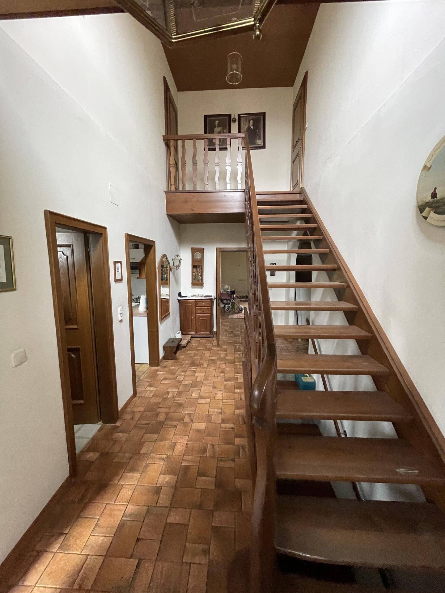 Geräumiger Flur mit Holztreppe, Fliesenboden und Holztüren, die zu weiteren Räumen führen.