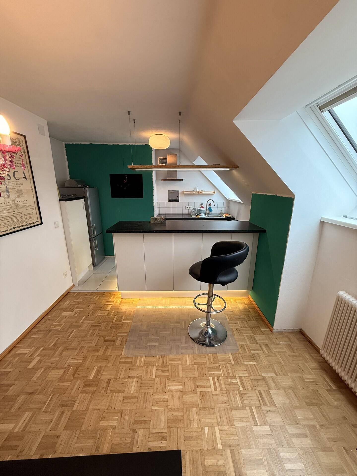 Moderne Küche mit Bartheke, Dachschräge und grüner Akzentwand.