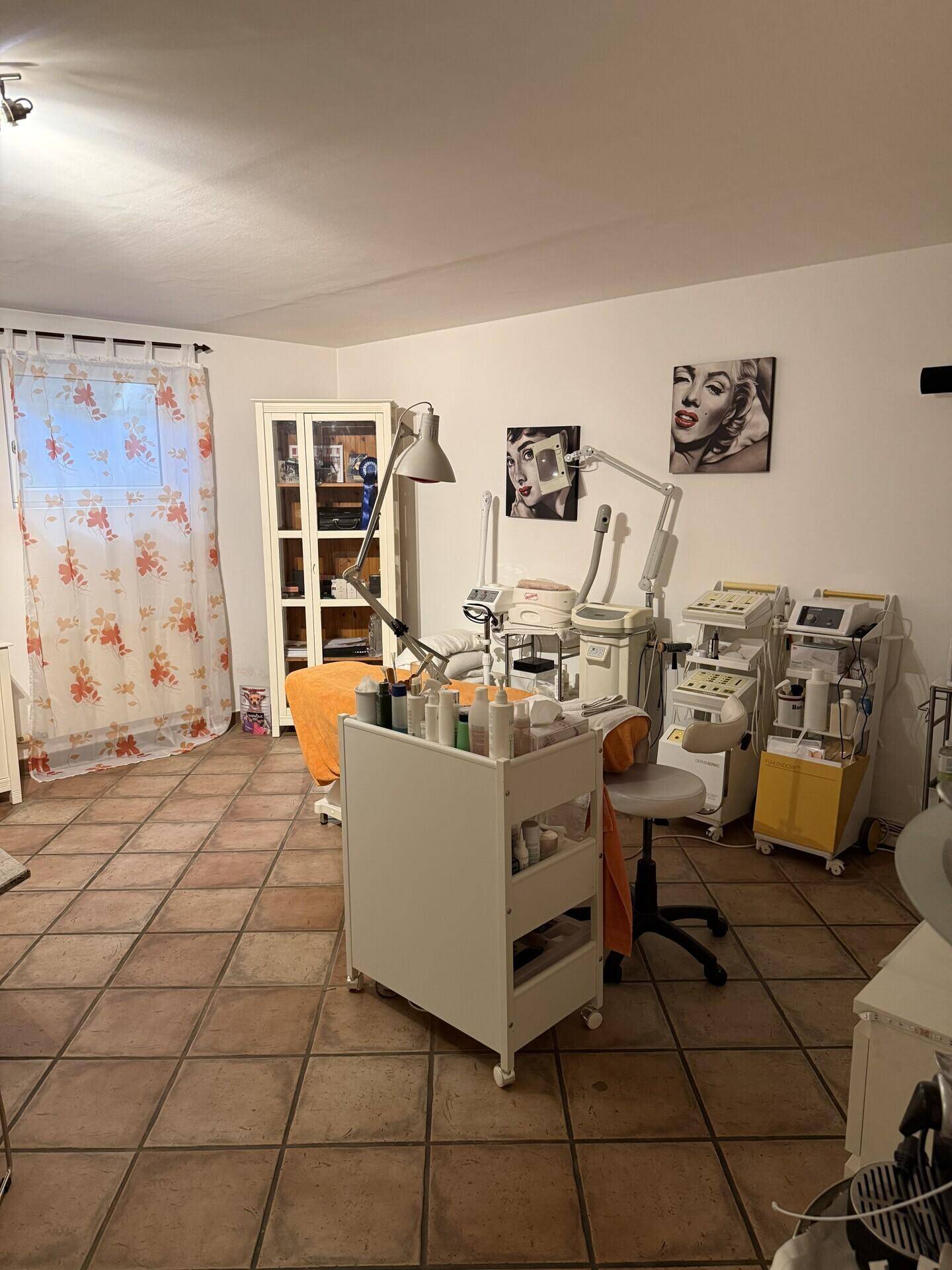 Raum mit Terrakottafliesen, ausgestattet als Kosmetikstudio mit Behandlungsgeräten.