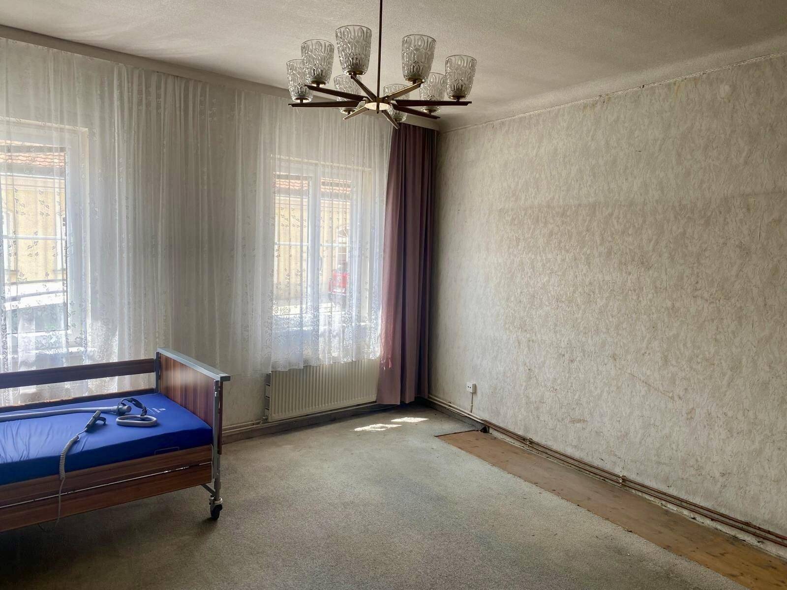 Geräumiges Zimmer mit Teppichboden, mehreren Fenstern und einem Pflegebett.