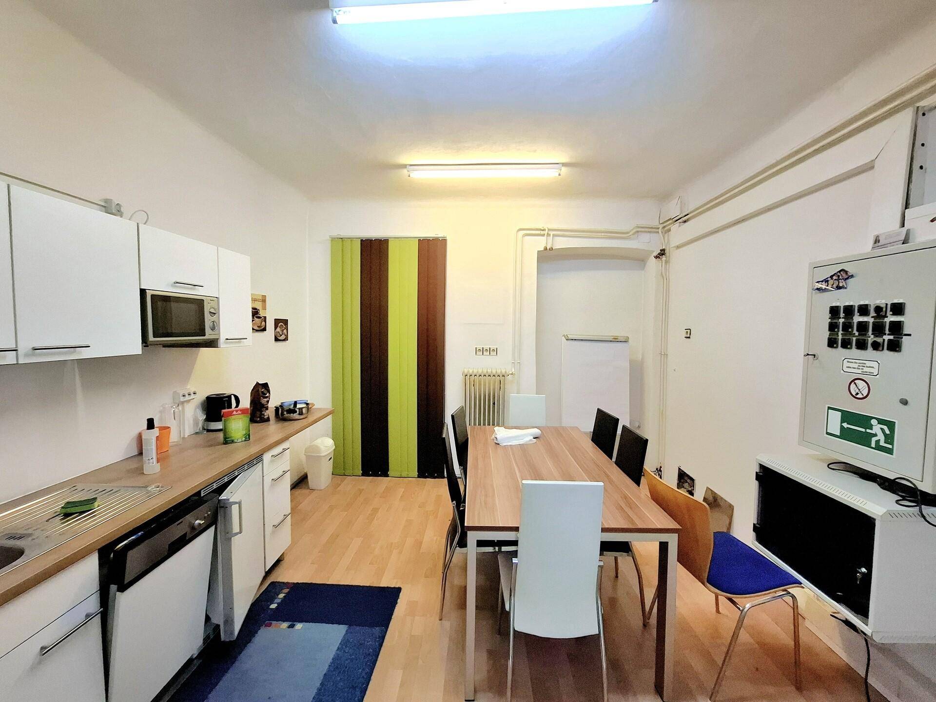 Funktionale Küche mit weißen Schränken, Esstisch und Stühlen, ideal für Pausen im Büro.