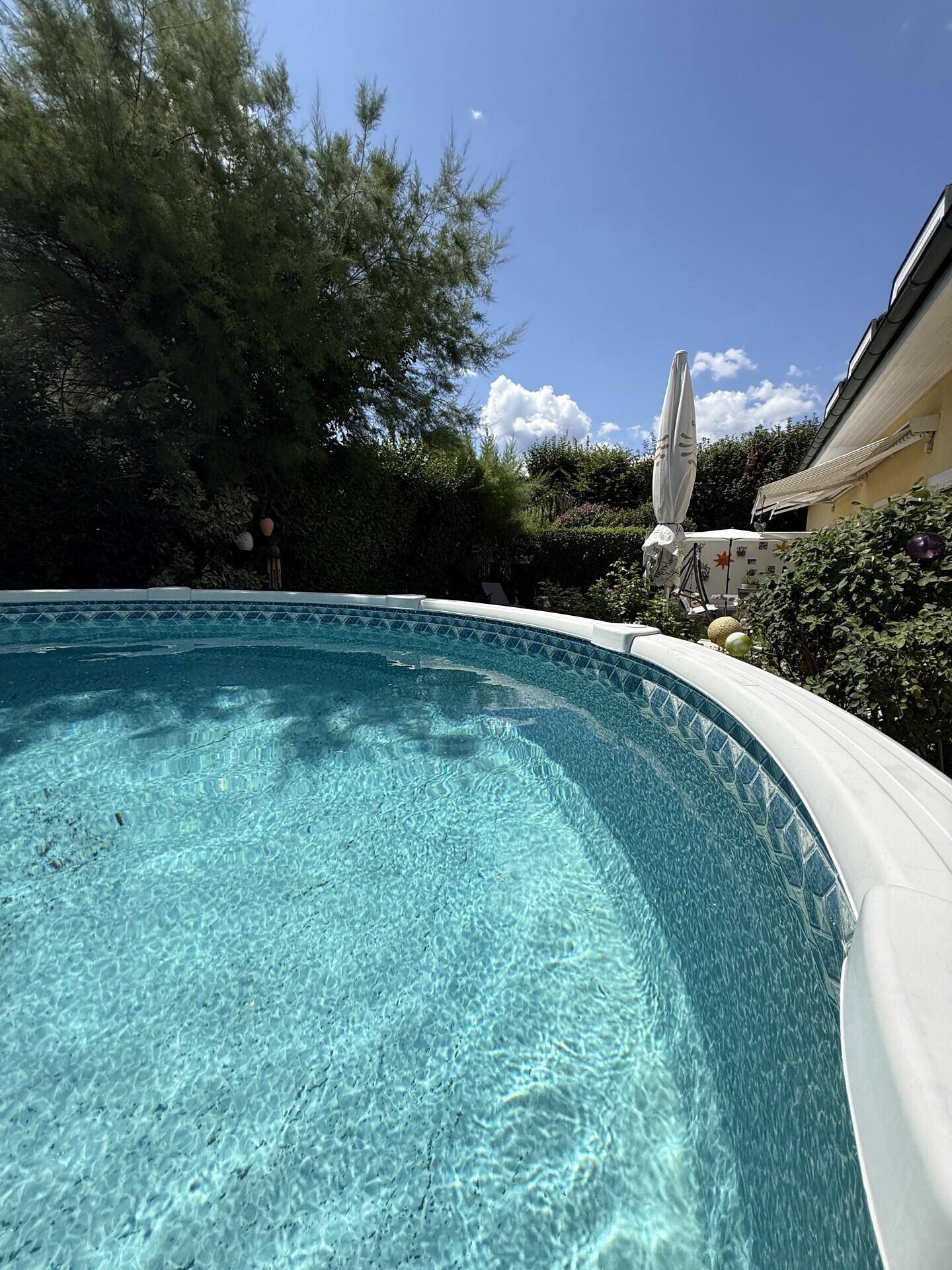 Nahaufnahme eines runden Aufstellpools im Garten unter blauem Himmel.