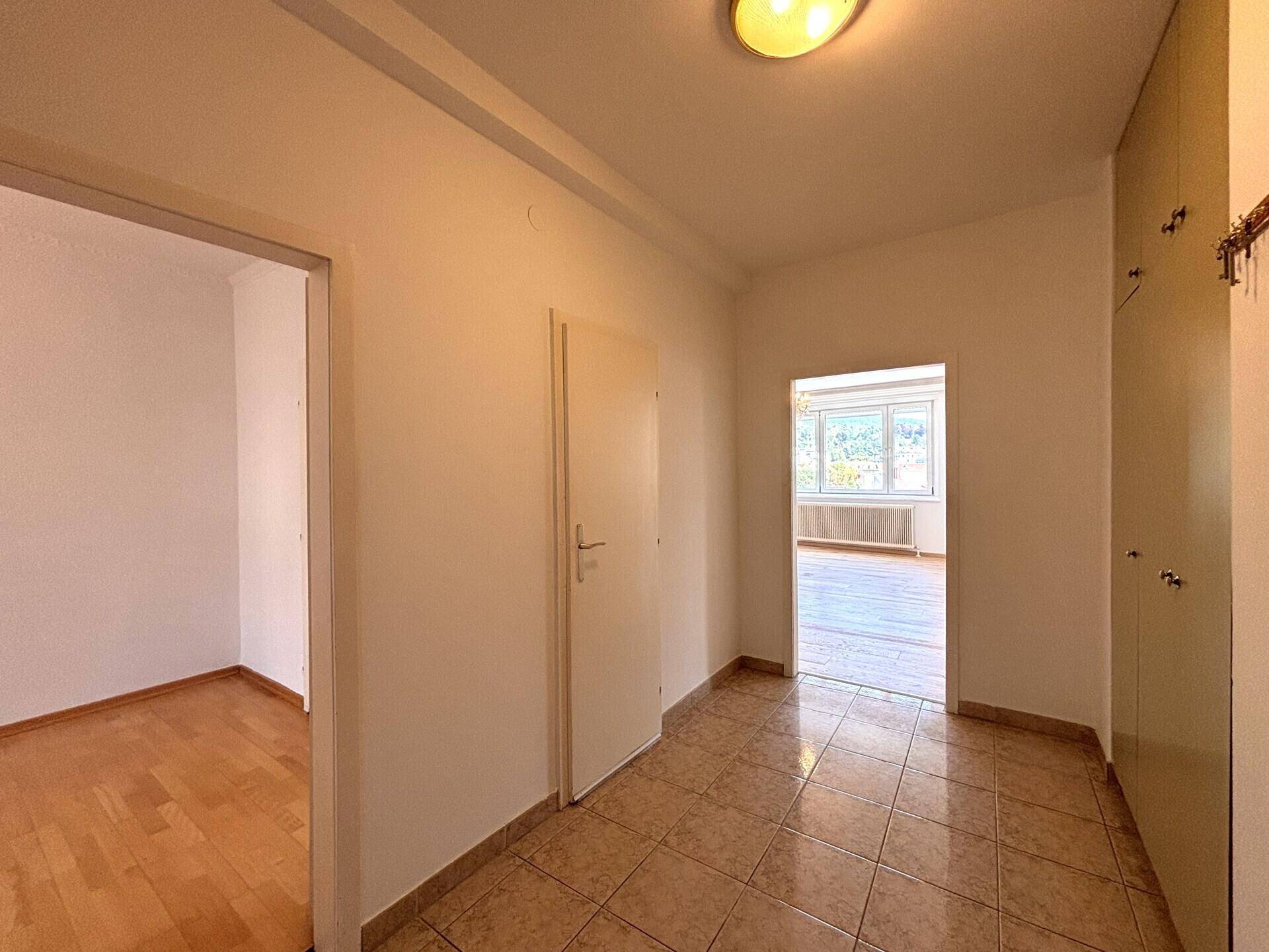 Heller Flur mit Fliesenboden und Zugang zu mehreren Zimmern, die Tageslicht erhalten.