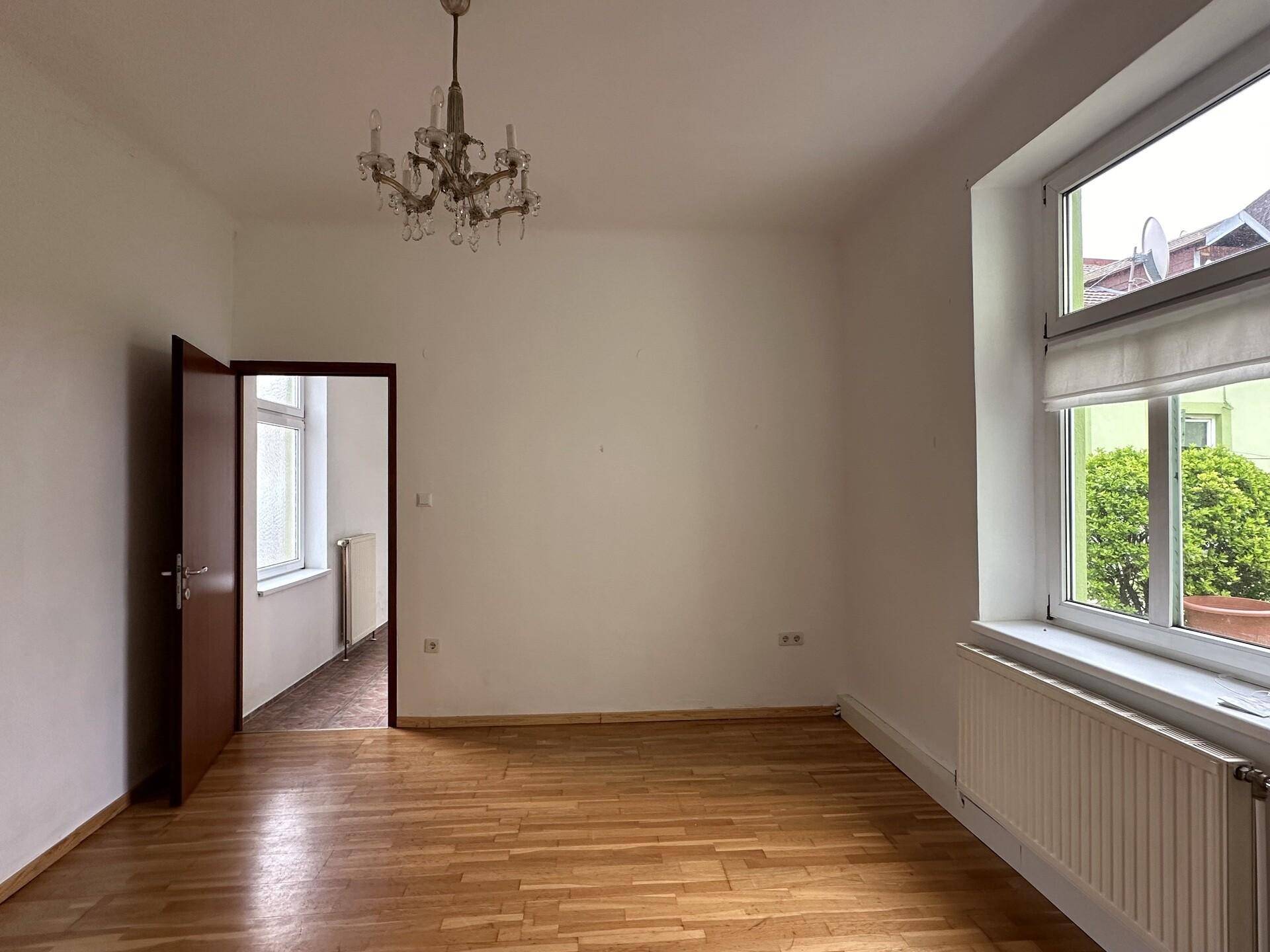 Helles Wohnzimmer mit Parkettboden und Kronleuchter, bietet viel Gestaltungspotenzial für neue Bewohner.