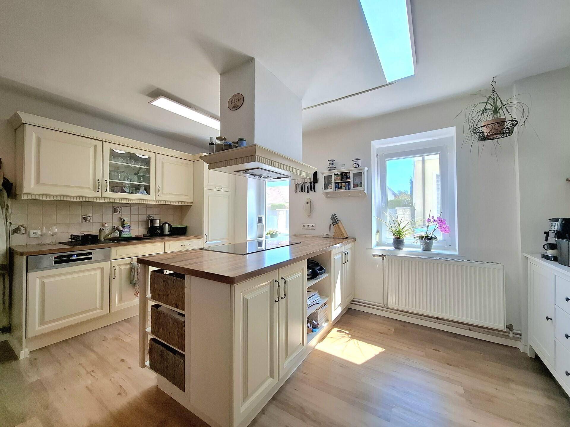 Freundliche Küche mit Kücheninsel, hellen Schränken und einem Fenster für natürliches Licht.