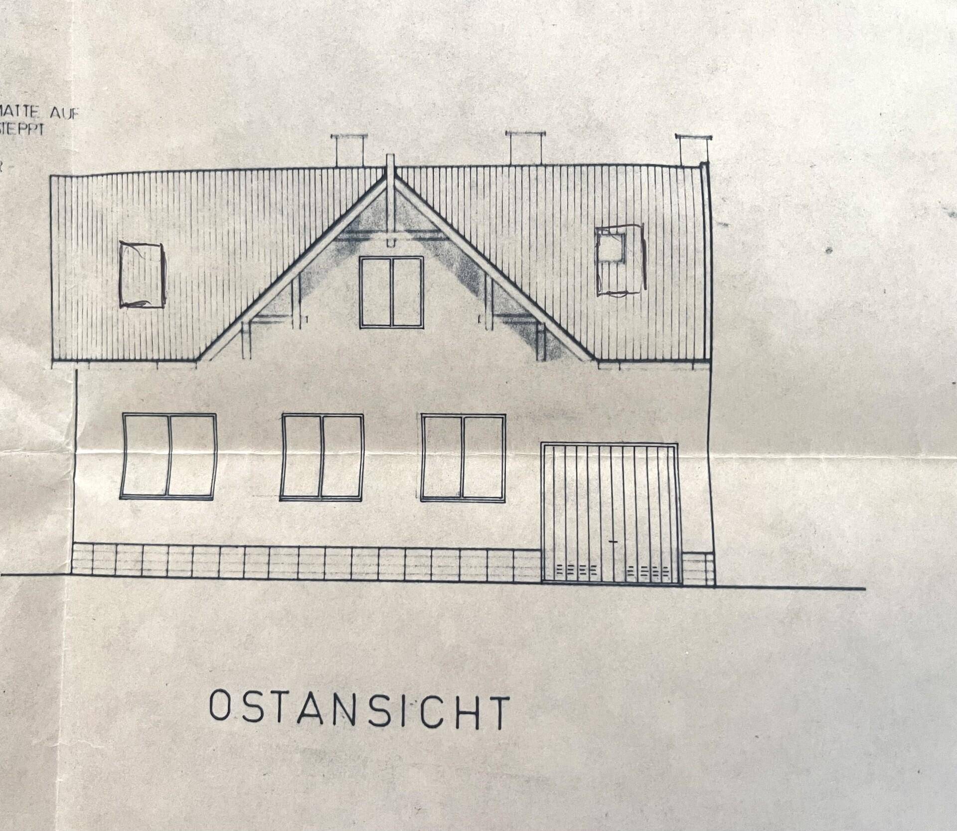 Ostansicht des Gebäudes mit Satteldach und mehreren Fenstern im Obergeschoss.