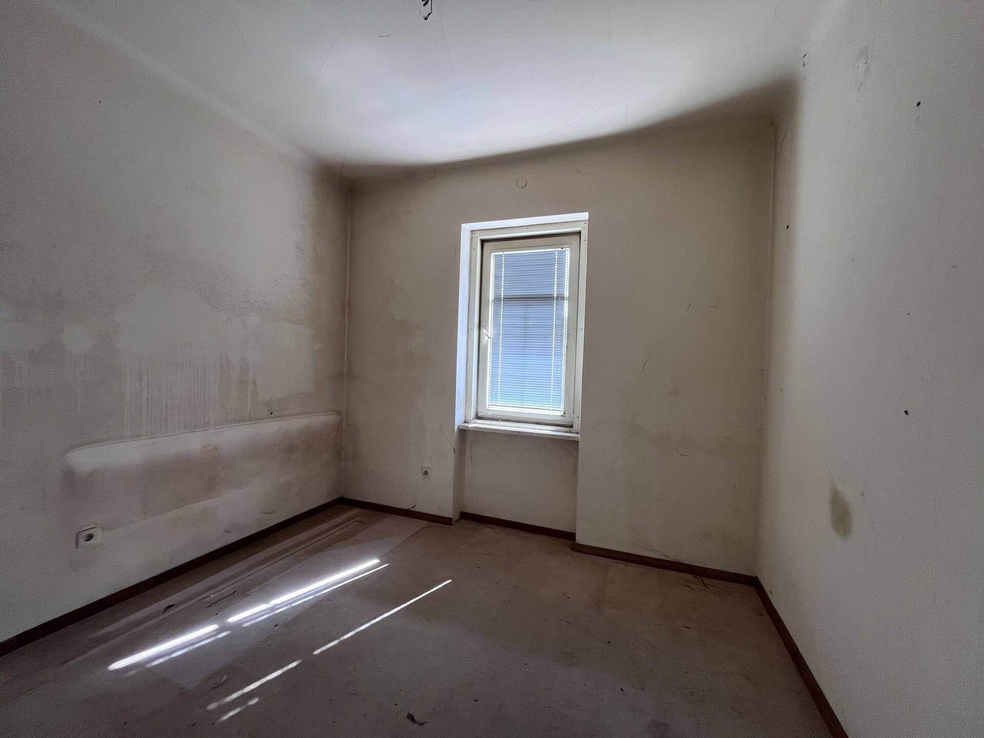 Kleines Zimmer mit einem Fenster und einfacher Ausstattung, ideal als Schlaf- oder Arbeitszimmer.