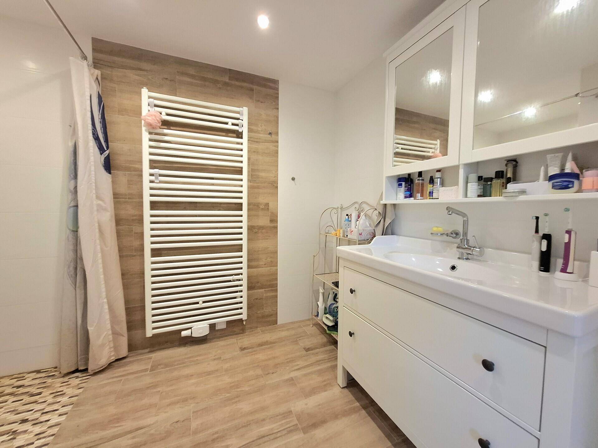 Modernes Badezimmer mit Dusche, Waschbeckenunterschrank und beheiztem Handtuchhalter.