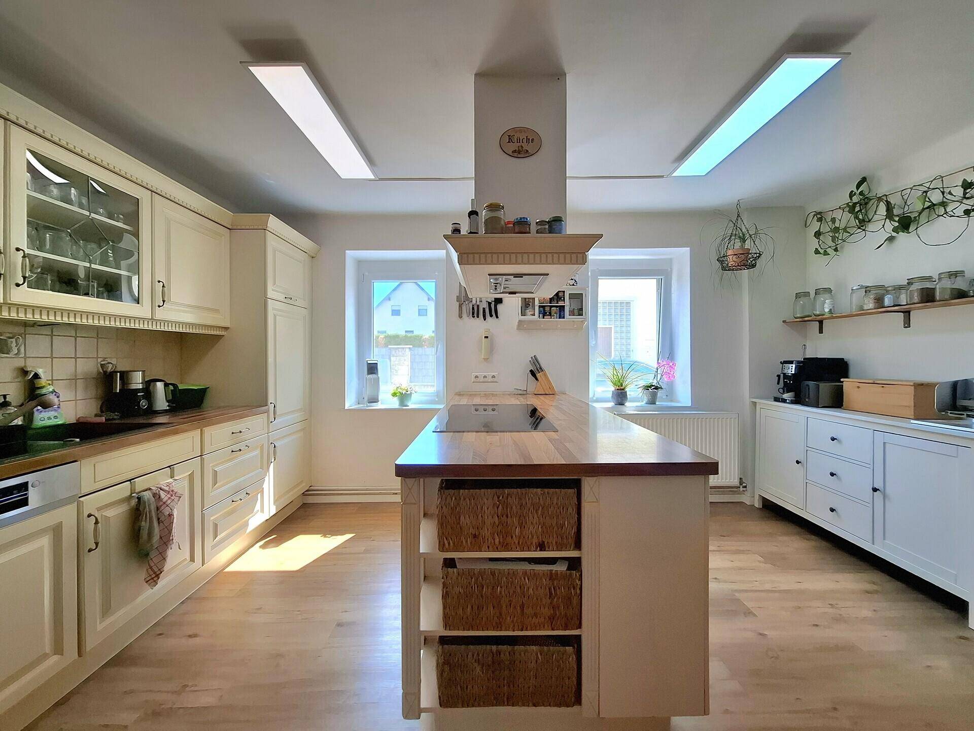 Moderne Küche mit heller Holzarbeitsplatte, integriertem Kochfeld und praktischen Körben in der Insel.