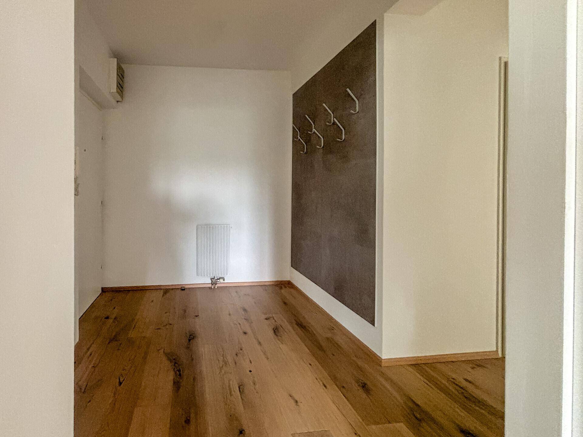 Heller Flur mit Holzboden und einer modernen Wandgestaltung mit Garderobenhaken.