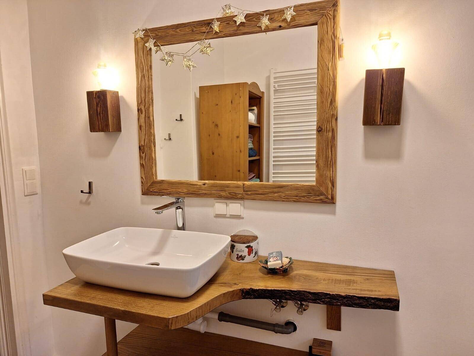 Modernes Badezimmer mit Holzwaschtisch, Aufsatzwaschbecken und Spiegel.