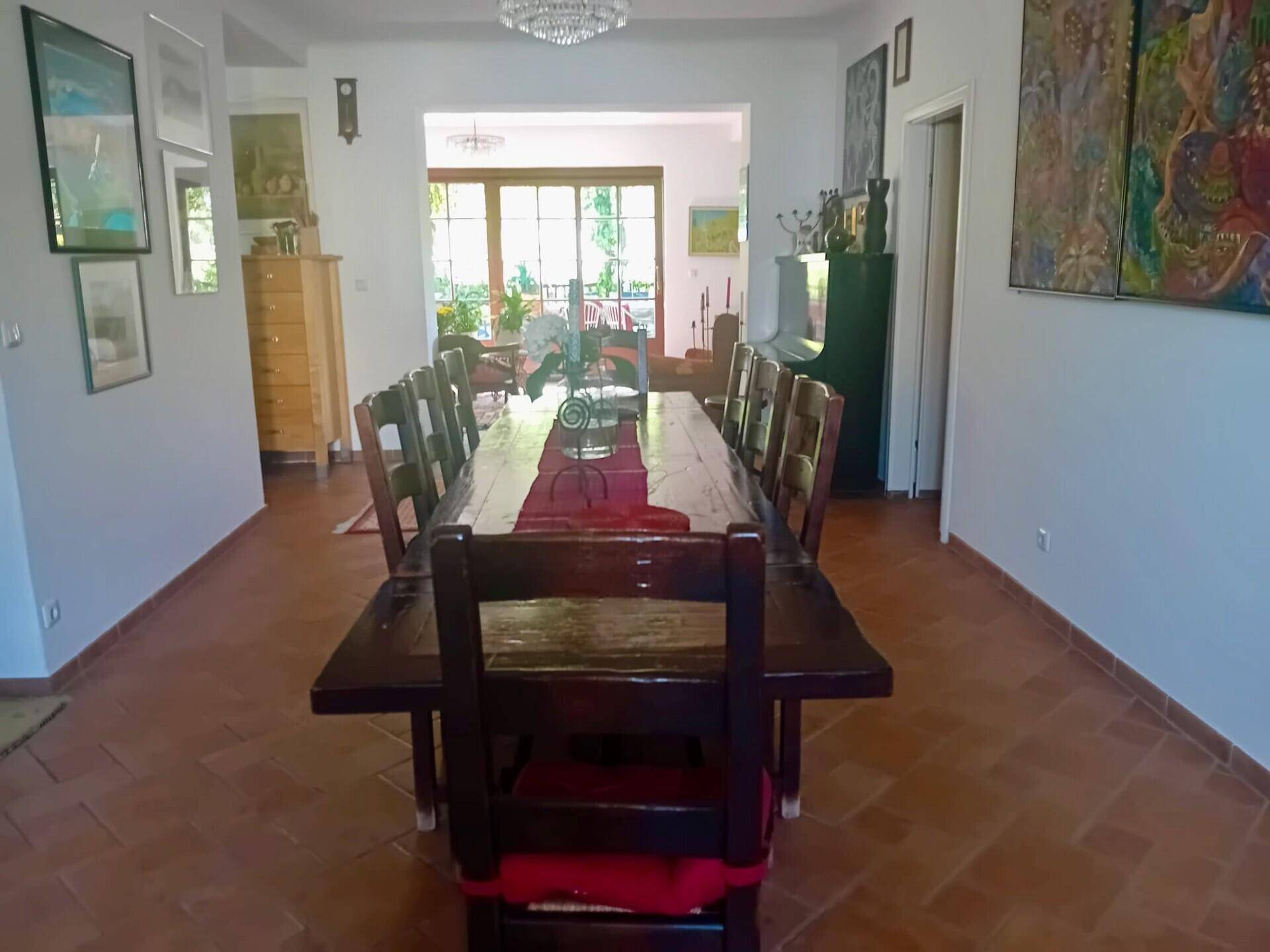 Geräumiges Esszimmer mit langem Holztisch, Terrakottaboden und Blick in den Gartenbereich.