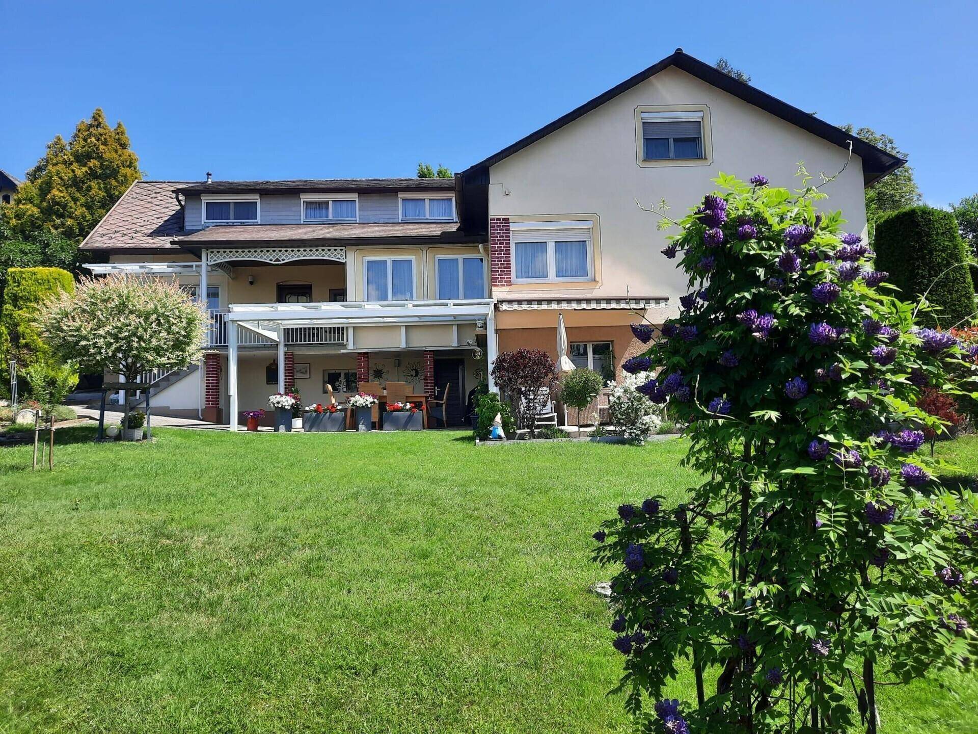Gepflegter Gartenbereich mit großer Rasenfläche und überdachter Terrasse am Haus.
