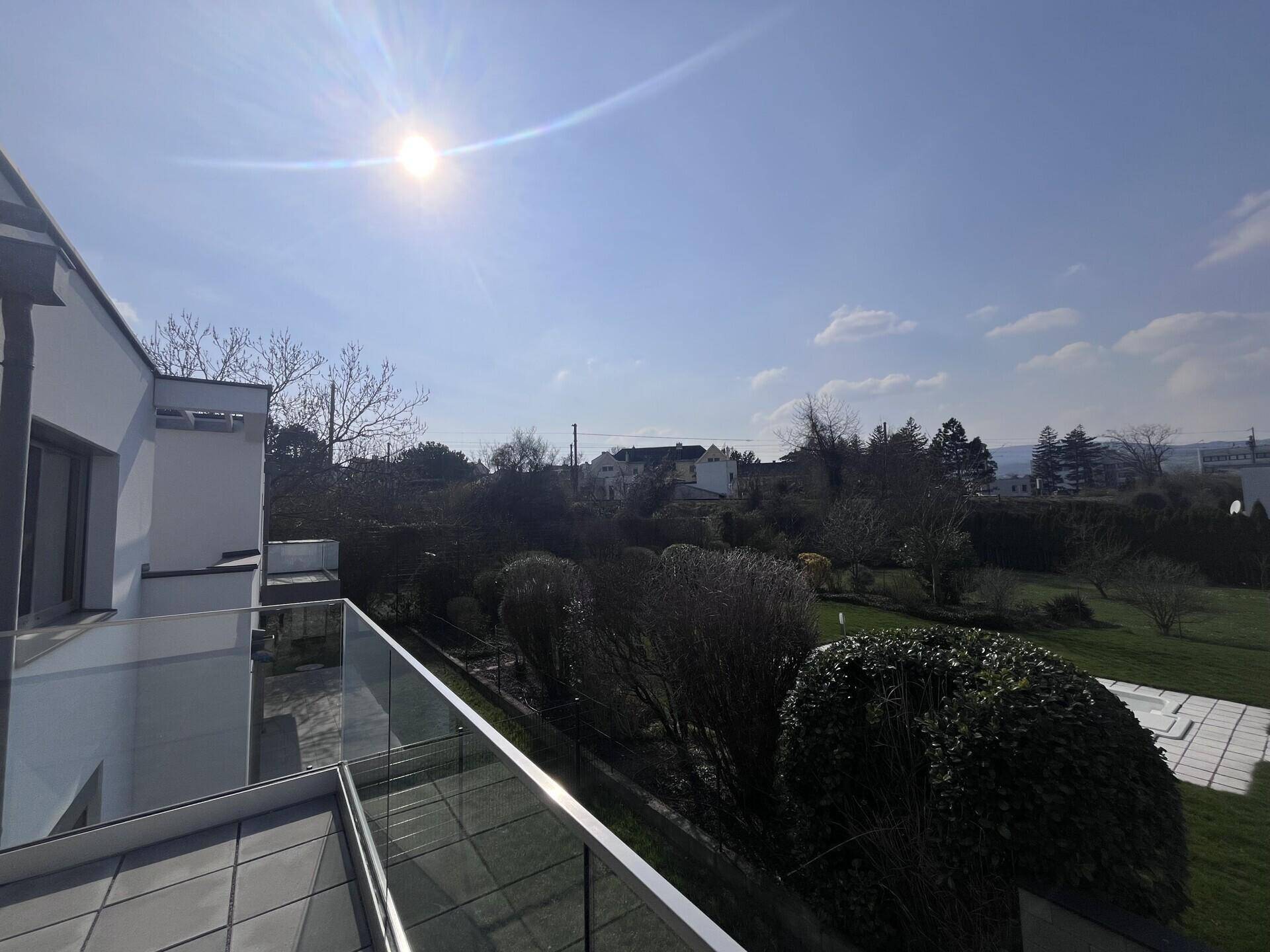 Weitläufiger Blick von der Terrasse auf die grüne Umgebung und den blauen Himmel.