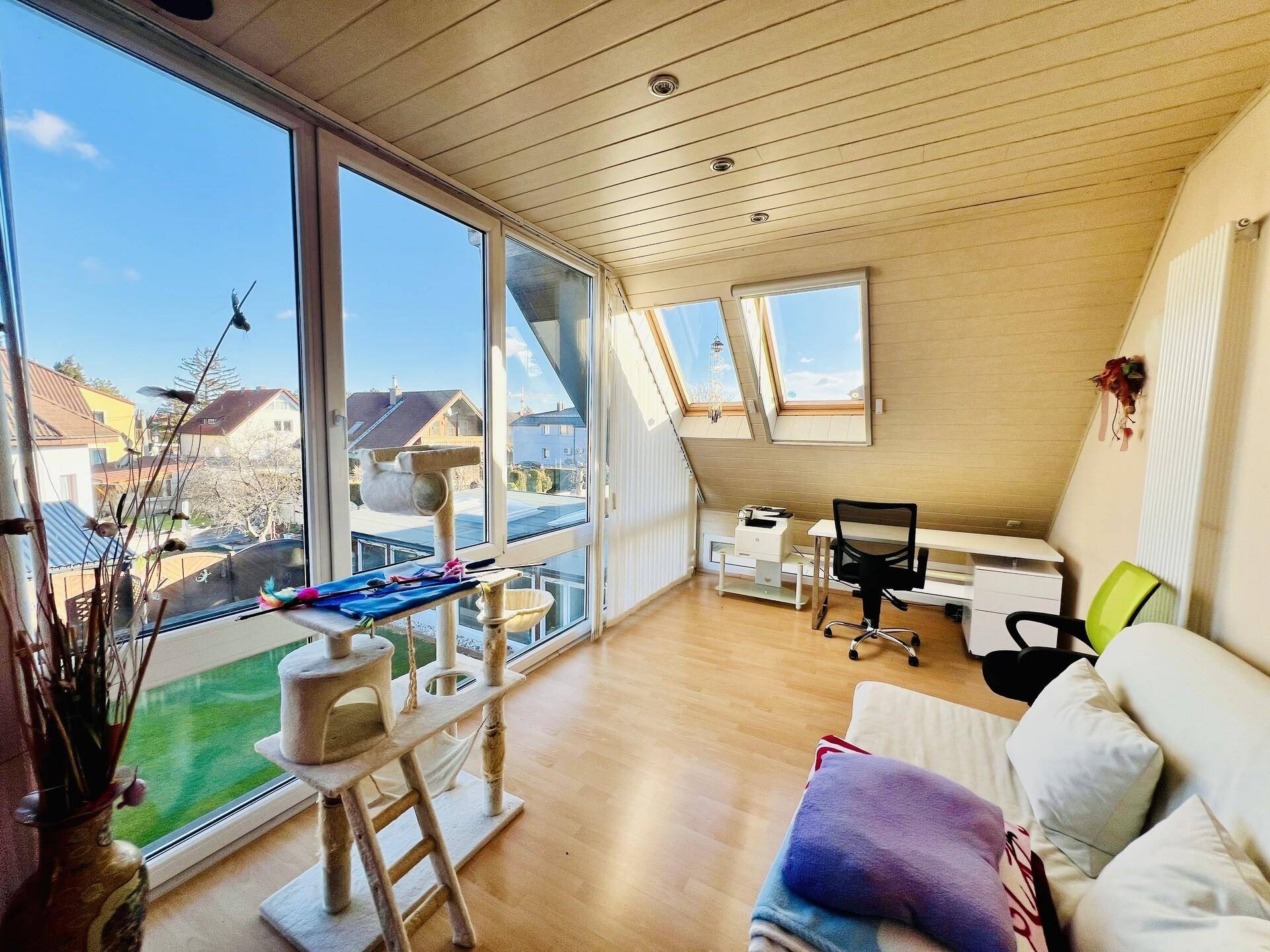 Helles Arbeitszimmer mit großen Fenstern, Holzboden und Blick auf die Umgebung.