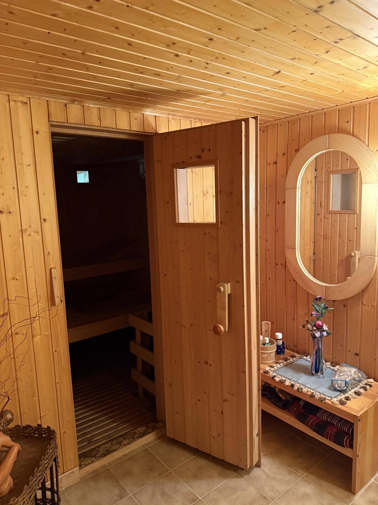 Geräumiger Saunaraum mit Holzwänden, Bänken und einem Spiegel, bereit zur Entspannung.